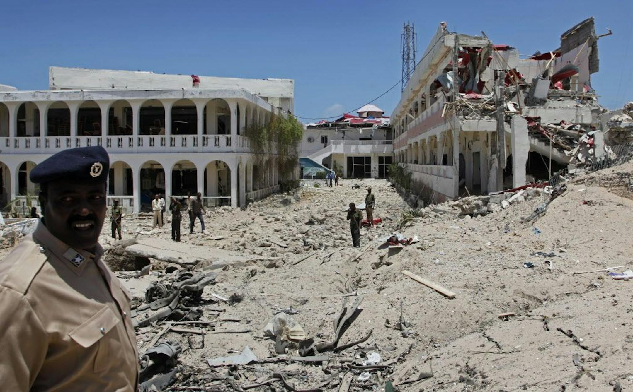 Somali soldiers stand near to a building destroyed by a blast near the presidential palace in the capital Mogadishu, Somalia Tuesday, Aug. 30, 2016. A suicide bomber has detonated an explosives-laden truck near the gate of Somalia's presidential palace in the capital on Tuesday, killing at least five people, police say.