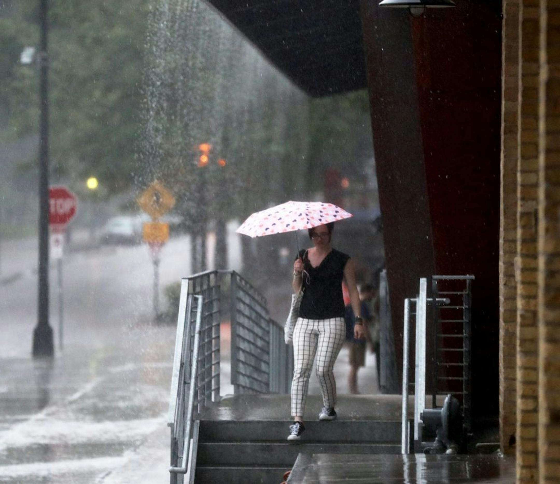 A person armed with an umbrella headed out into the rain along Main Street as a storm hits Thursday in Minneapolis. The Twin Cities will get a second round of heat and severe weather this week.