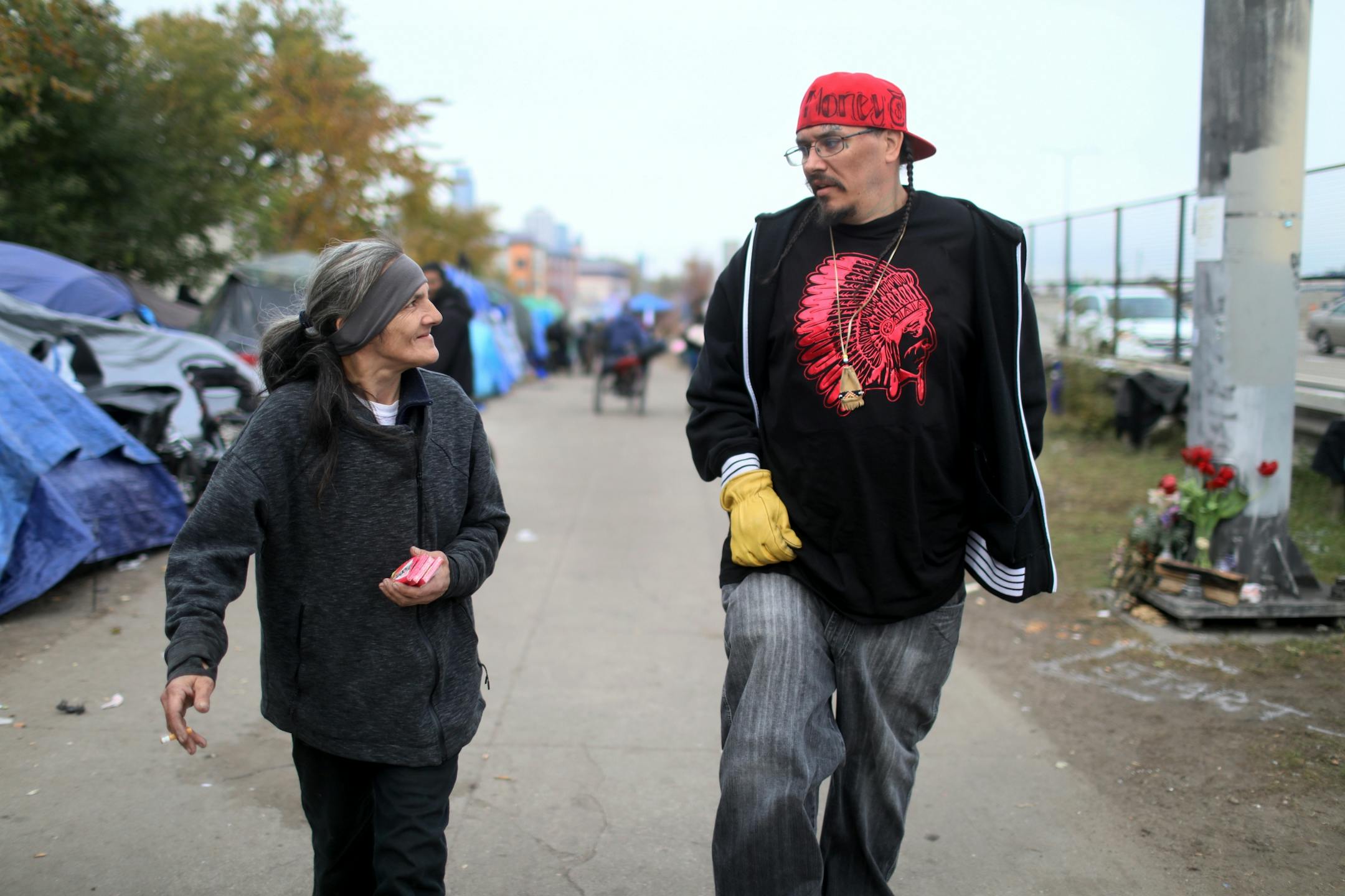 This week, after months of living at a crowded homeless camp, Mike and Ellen Eagletail and their three children finally moved into a place of their own. They are among a small but growing number of people at a south Minneapolis homeless camp who are starting to find housing. Here, Mike Eagletail walks with a woman living in the encampment to where she saw a male physically abusing a woman Thursday, Oct. 25, 2018, in Minneapolis, MN.