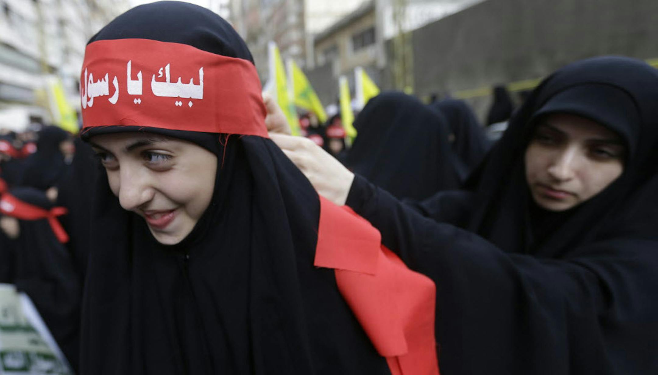 A veiled Hezbollah supporters ties a banner on her friend's forehead, that reads in Arabic, "At your service God's prophet," during a rally denouncing an anti-Islam film that has provoked a week of unrest in Muslim countries worldwide, in the southern suburb of Beirut, Lebanon, Monday.