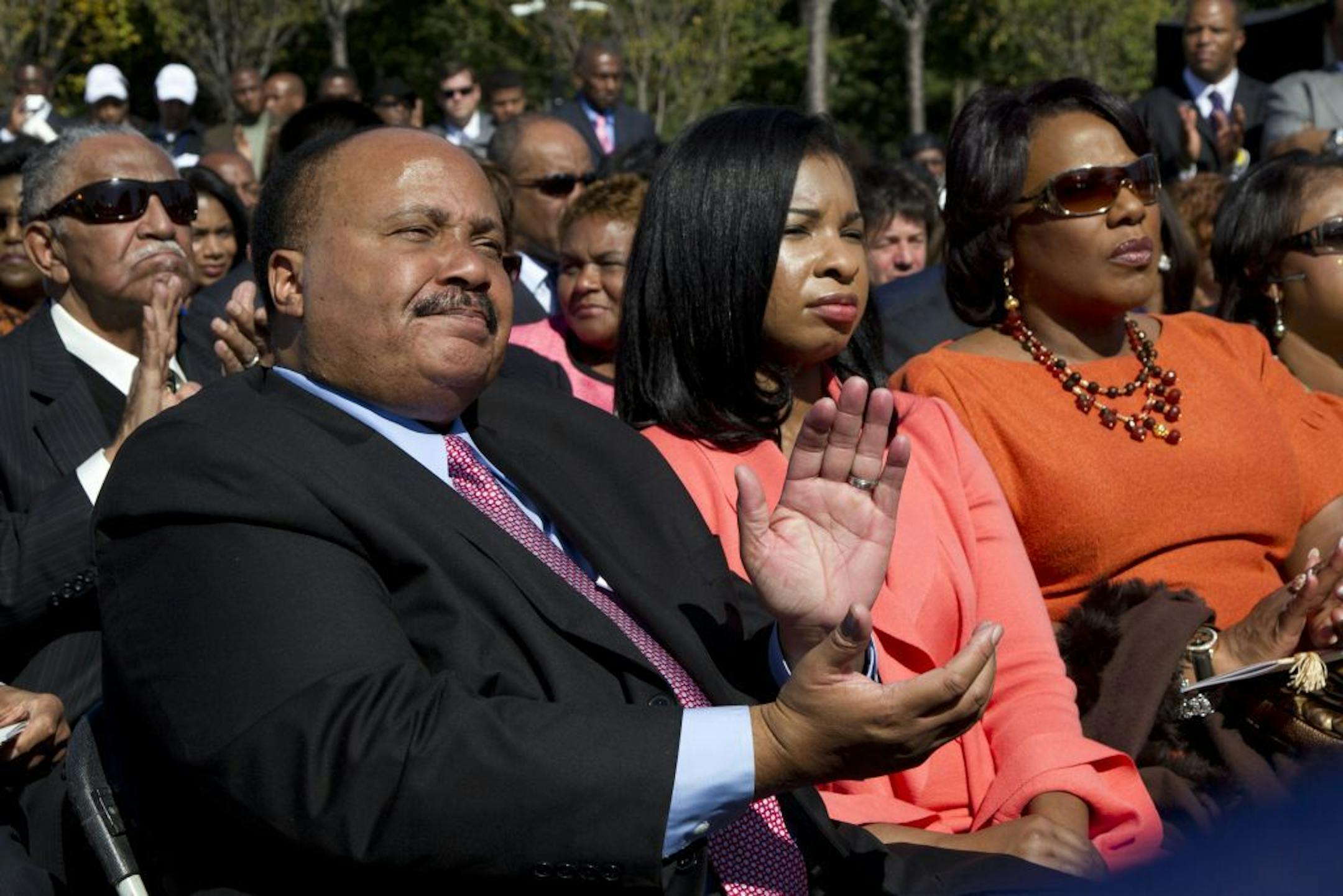 Martin Luther King, III, left, his wife Arndrea King, center, and Bernice King listen to President Barack Obama speaks during the dedication ceremony for the Martin Luther King Jr. Memorial Sunday, Oct. 16, 2011, on the National Mall in Washington.