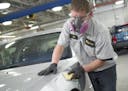 An Abra Auto Body employee works on a vehicle.