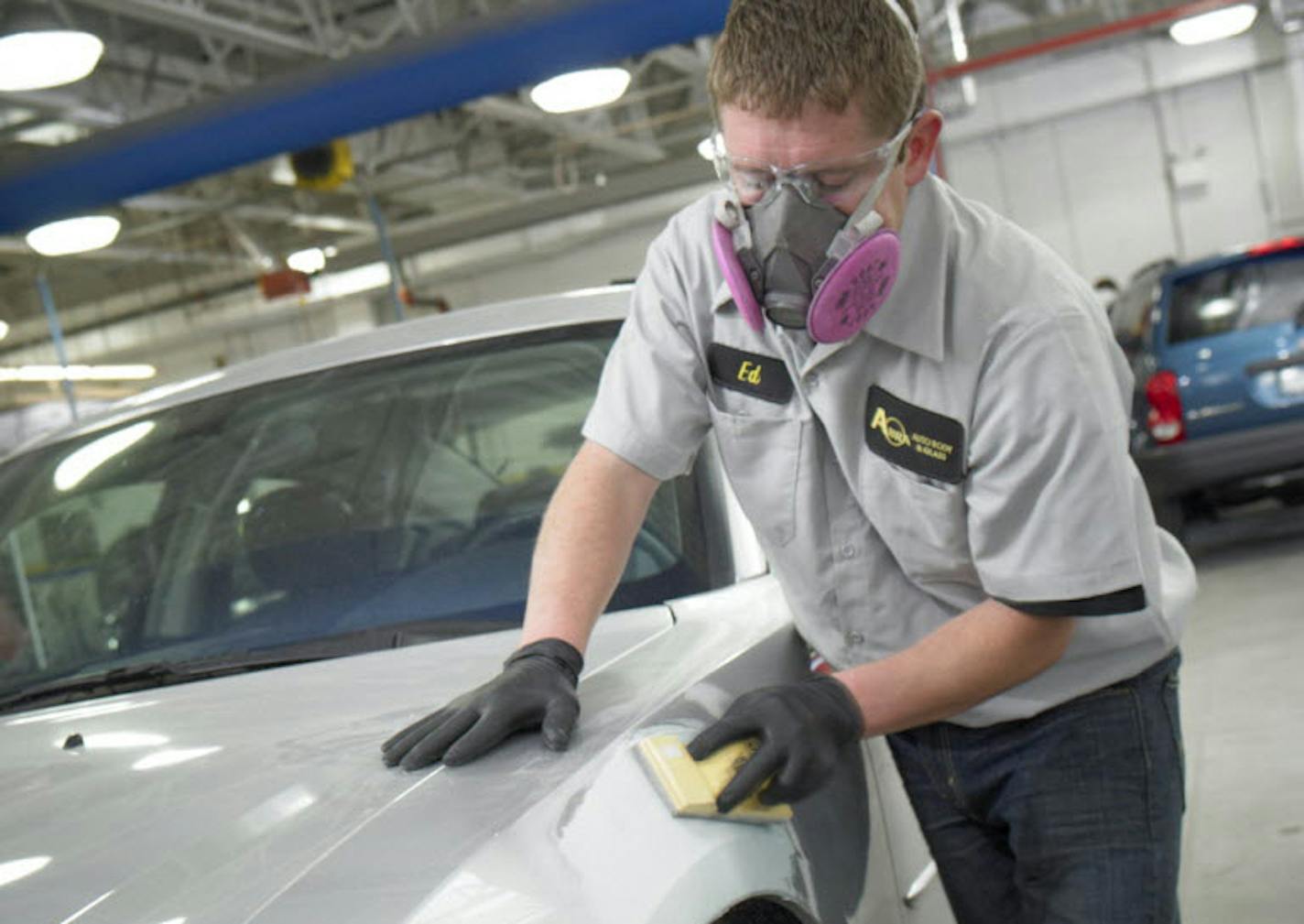 An Abra Auto Body employee works on a vehicle.