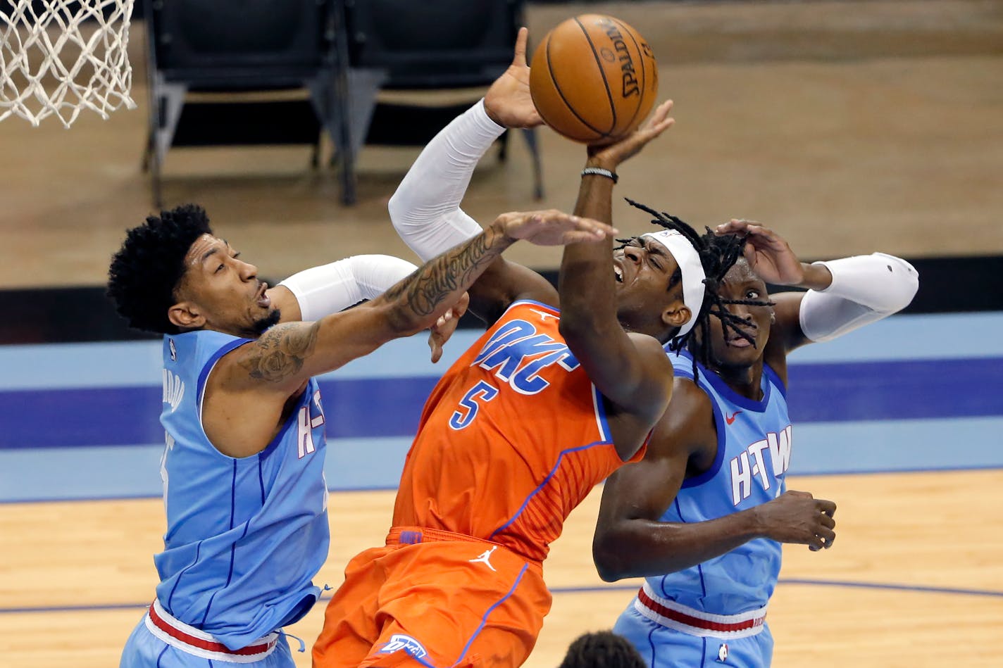 Oklahoma City Thunder forward Luguentz Dort (5) drives up a shot between Houston Rockets center Christian Wood, left, and guard Victor Oladipo, right, during the first half of an NBA basketball game Sunday, March 21, 2021, in Houston. (AP Photo/Michael Wyke)