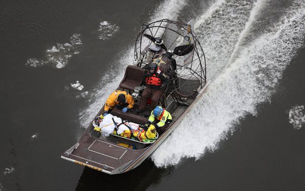 Rescue personnel transfer an accident victim by airboat down the Mississippi River, seen from the Franklin Avenue Bridge, Tuesday, Dec. 27, 2016, in M