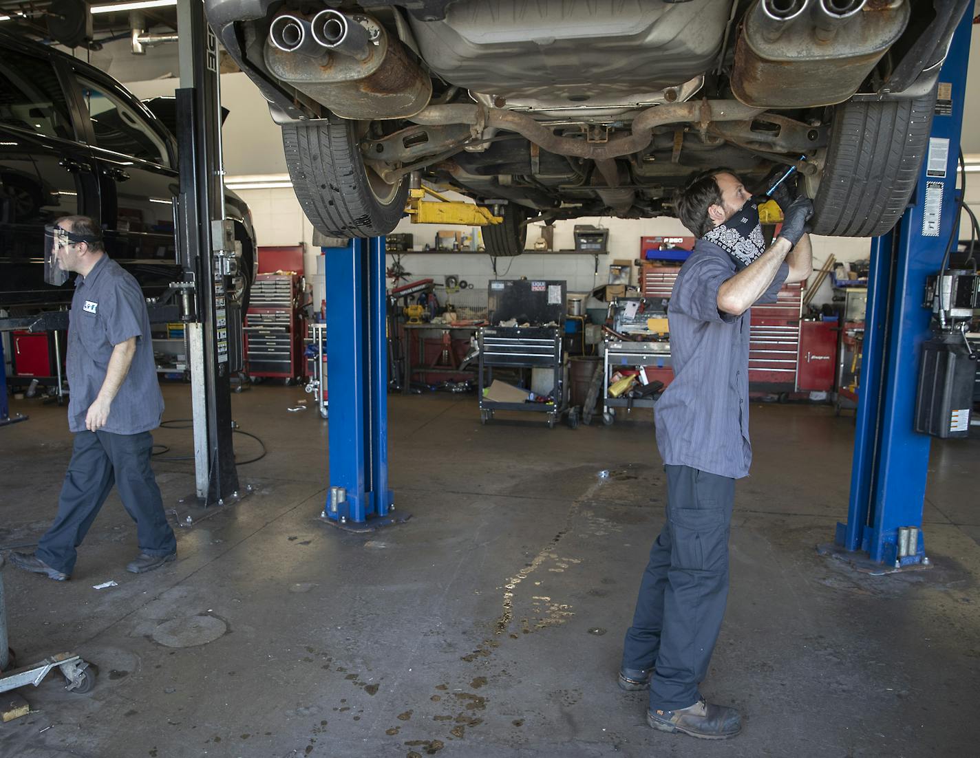 Car mechanics Zach Stuen, right, and John Buttner, left, worked on cars at Lift Garage, Friday, July 24, 2020 in Minneapolis, MN. The Minneapolis nonprofit on East Lake Street is surrounded by businesses burned down or damaged along East Lake Street. The garage is a small nonprofit that repairs cars for people in need. It remained untouched during the Minneapolis riots in June and hasn't stopped working. ] ELIZABETH FLORES • liz.flores@startribune.com