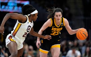 Iowa guard Caitlin Clark (22) drives up court past South Carolina guard Raven Johnson, left, during the first half Sunday in Cleveland.