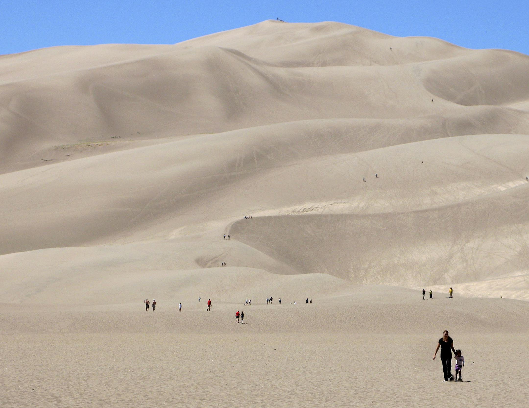 This Saturday, Aug. 14, 2010 photo shows visitors as they walk near the base of the dune field at Great Sand Dunes National Park and Preserve in Mosca, Colo. The dunes can reach heights of 750 feet. (AP Photo/Thomas Peipert) ORG XMIT: NYLS503