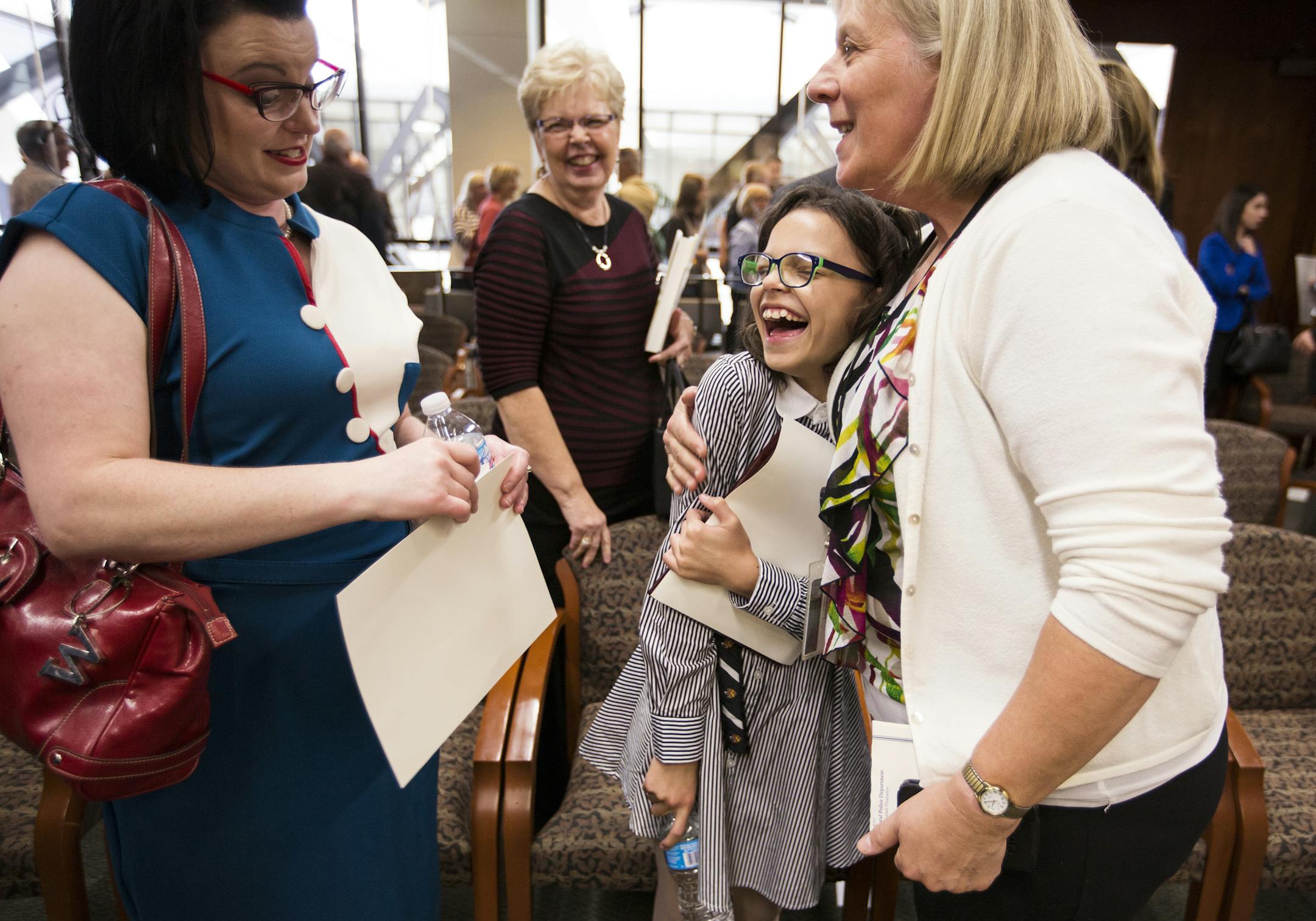 Thalia Williams, 11, standing with her mother Julia Williams, left, is congratulated by Therese Lockwood, right, a Hennepin County victim witness advocate who worked on her case, before accepting the outstanding citizen award during the Hennepin County Attorney's Office Community Leadership Awards ceremony at the Hennepin County Government Center in Minneapolis on Friday, October 2, 2015. ] LEILA NAVIDI leila.navidi@startribune.com / BACKGROUND INFORMATION: Thalia Williams, 11, bravely testified