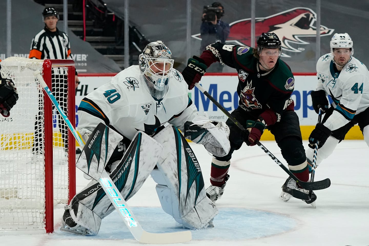 San Jose Sharks goaltender Devan Dubnyk protects the net against Arizona Coyotes center Christian Dvorak (18) as Sharks defenseman Marc-Edouard Vlasic looks on during the third period of an NHL hockey game Saturday, Jan. 16, 2021, in Glendale, Ariz. The Coyotes defeated the Sharks 5-3. (AP Photo/Ross D. Franklin)