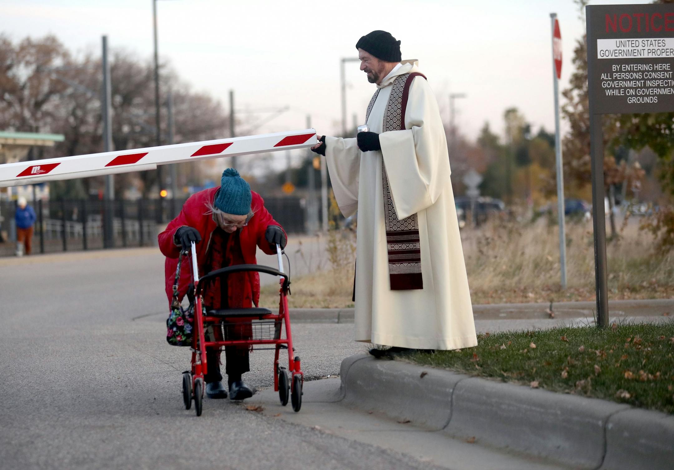 A clergy member who did not want to give his name assists a woman making it through a crossing gate outside the Whipple Federal Building Tuesday, Oct. 29, 2019, in St. Paul, MN. Clergy and protestors gathered for a service and communion outside the Whipple Federal Building and to protest the naming of the building after the Episcopal bishop because deportations and other actions at the courthouse are in opposition to the beliefs of the Episcopal church, they stated.