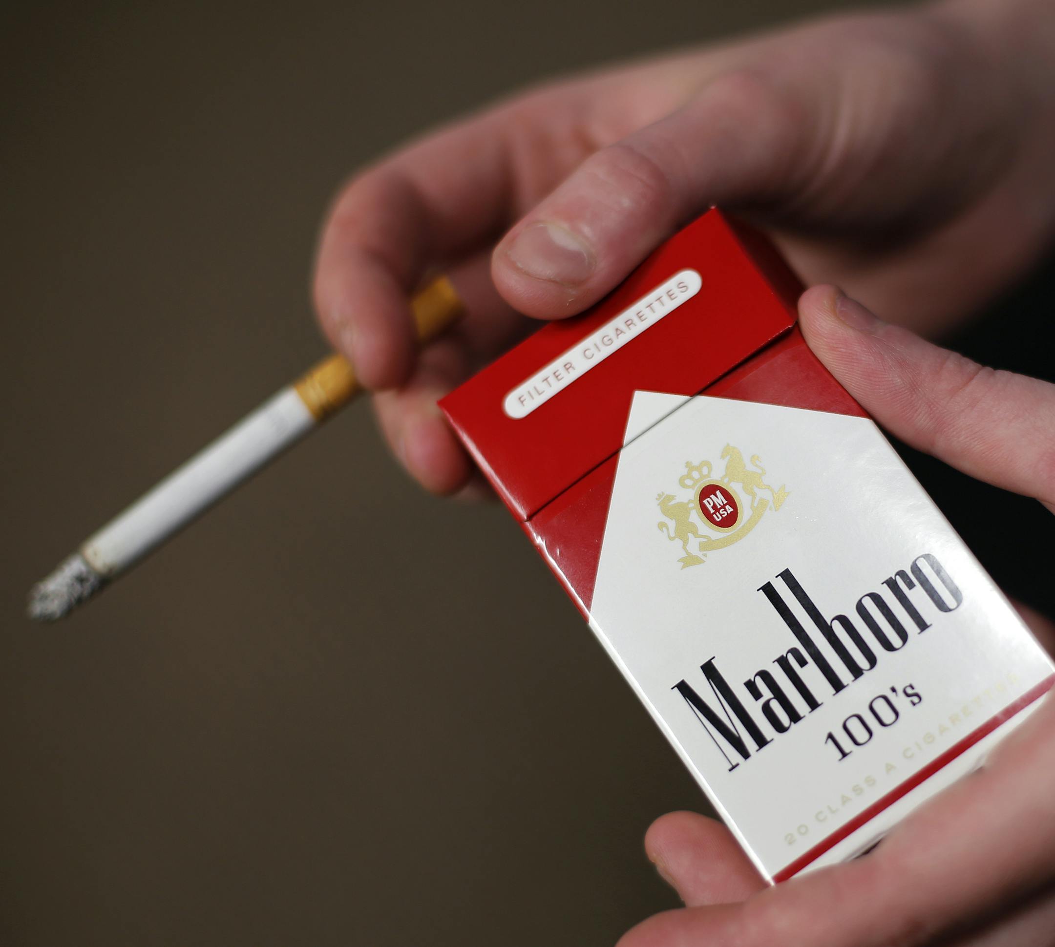 In this photo taken July 17, 2015, store manager Stephanie Hunt poses for photos with a pack of Marlboro cigarettes, an Altria brand, at a Smoker Friendly shop in Pittsburgh. Altria reports quarterly financial results on Wednesday, July 29, 2015. (AP Photo/Gene J. Puskar)
