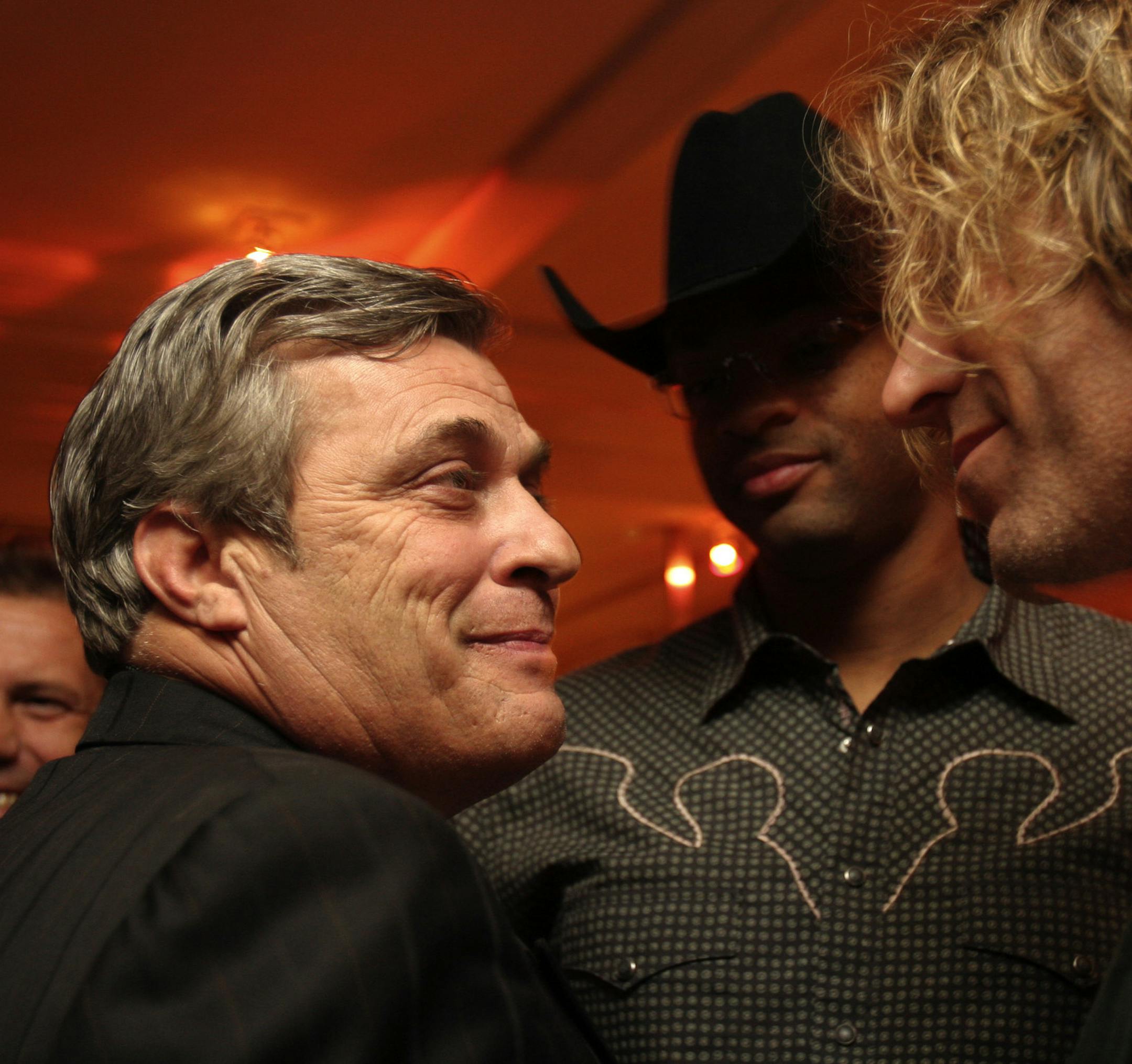 PHOTO BY SCOTT LEWIS/SPECIAL TO STAR TRIBUNE. Mick Anselmo talks with Big Kenny of Big and Rich, with Cowboy Troy in the background, during a Clear Channel party for the Country Music Awards. Anselmo is the general manager of K102, the CMA's metro-market country music radio station of the year.