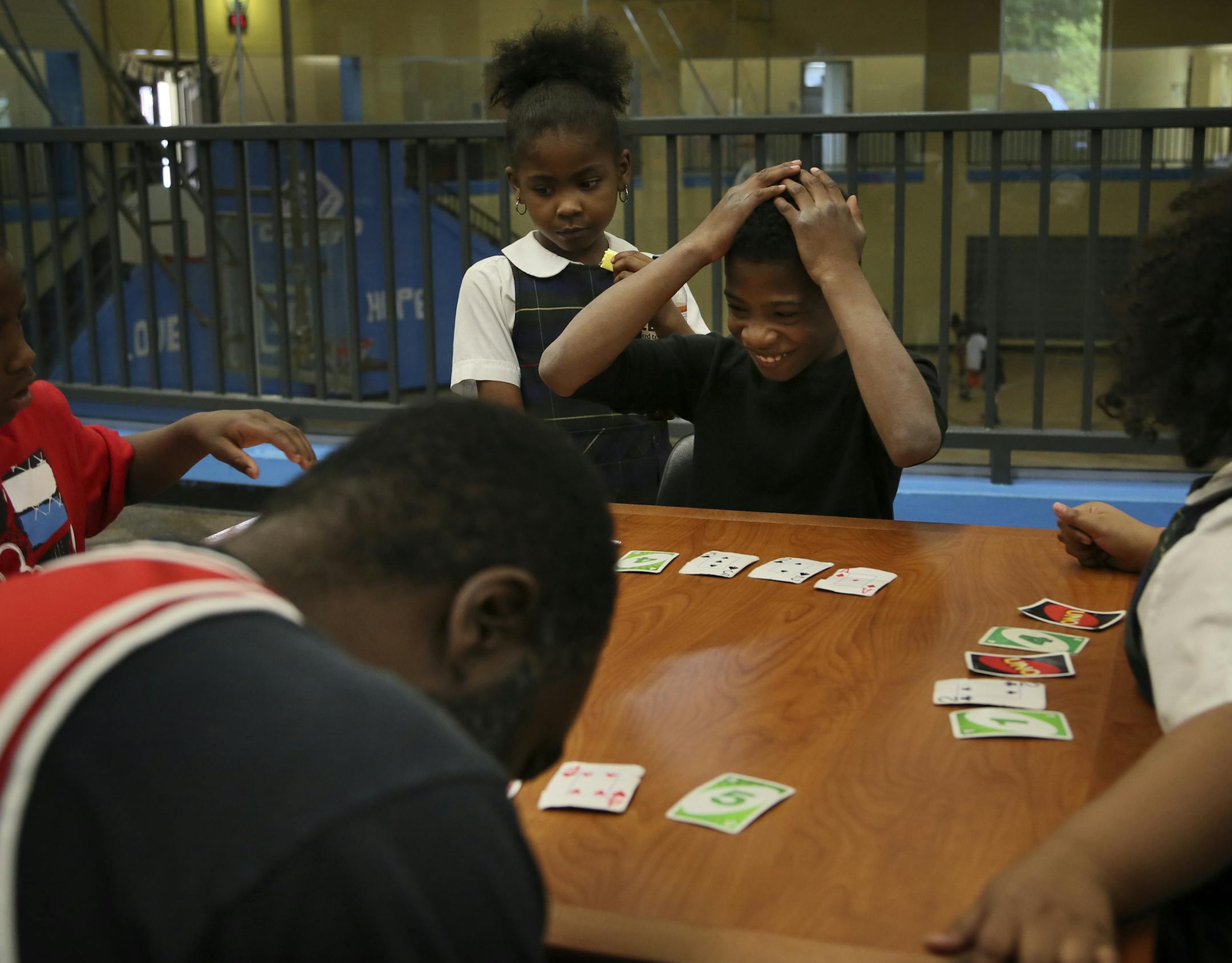 It might just look like kids playing pool and ping pong, but the staff at Jerry Gamble Boys and Girls Club have set up the game room in a way that kids have to obey and maintain the rules themselves. Here, Xavier Turner, 9, reacts to coach John Bryant, foreground, winning in a card game called "fives" Friday, May 25, 2013 in Minneapolis, MN. Those hoping to get a chance to play must stand patiently behind and wait their turn.](DAVID JOLES/STARTRIBUNE) djoles@startribune Concerns about the social