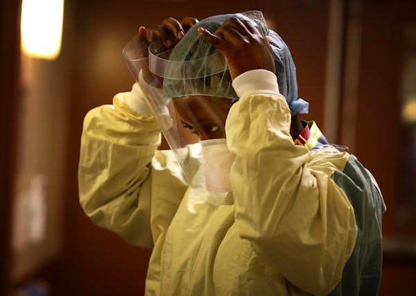 Syndie Pascal, an RN, donned personal protective equipment before checking a COVID-19 patient on the fifth floor ICU at Bethesda Hospital Thursday, Ma