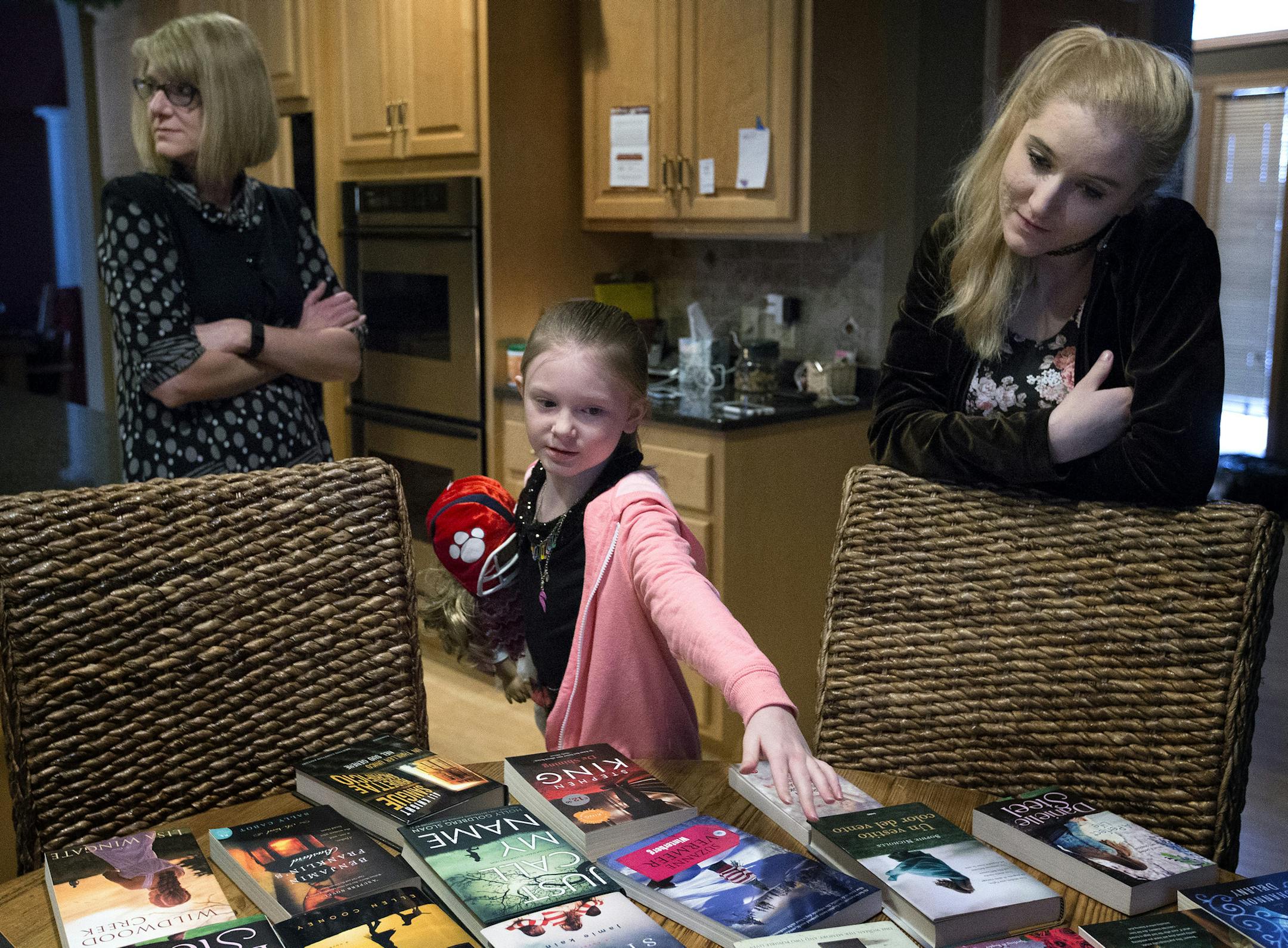 “I have to try to look sad a lot,” said Niamh Ansley, perusing book covers on the kitchen table with mom Elisabeth and big sister Chaeli.