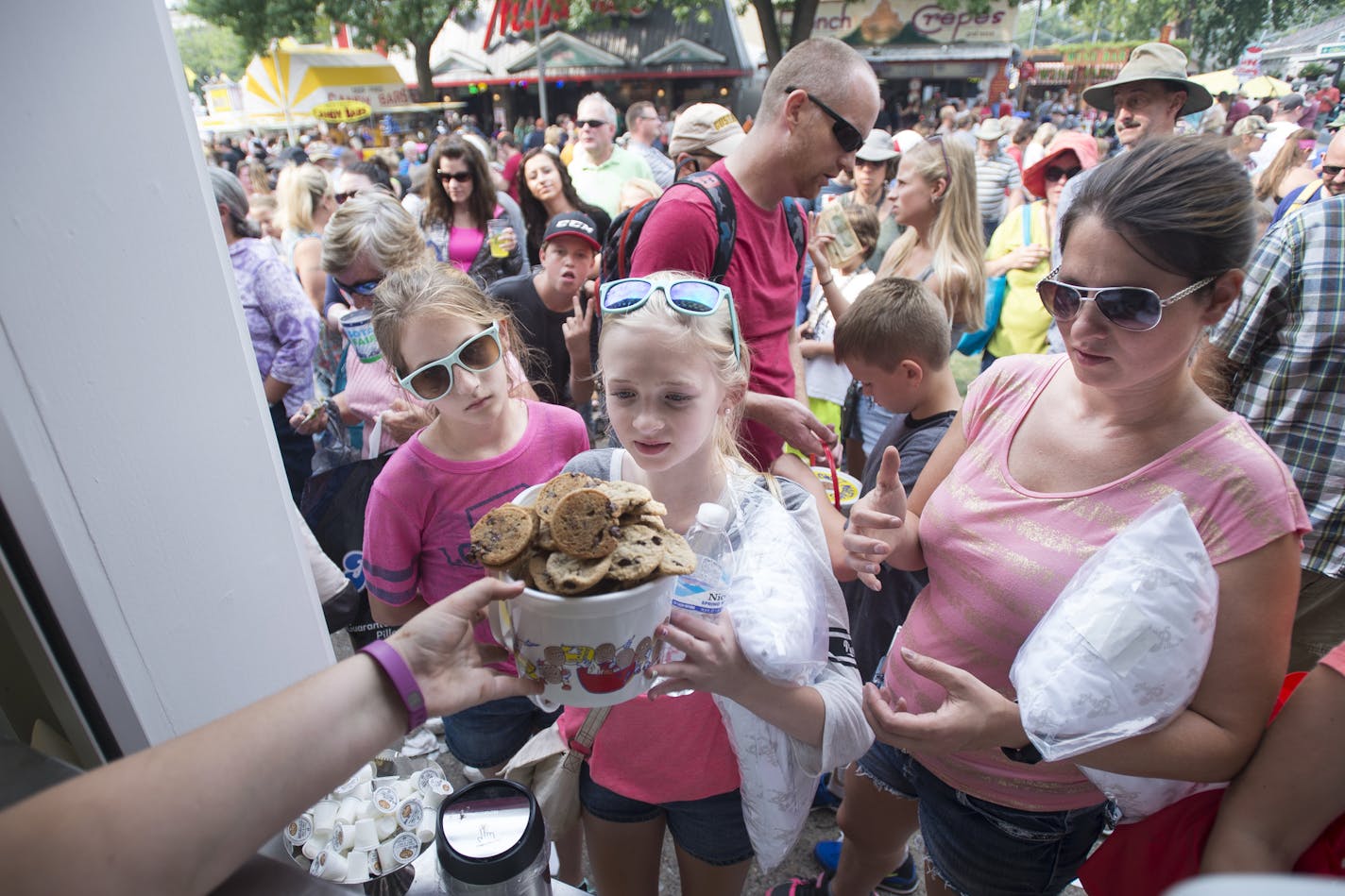 Jenna Mueller,11, watched as her friend Reise Jones, 11, was handed a bucket of cookies alongside Christy Mueller Thursday at Sweet Martha's Cookie Jar.