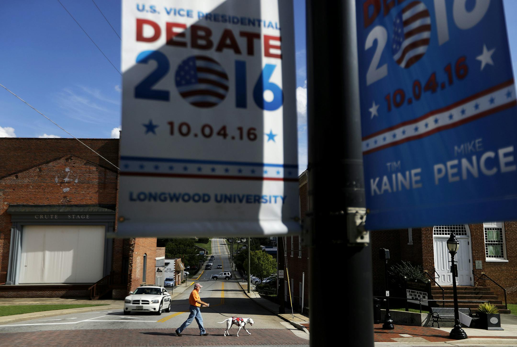 A pedestrian crosses a street as signs advertising the vice presidential debate hang along South Main Street in Farmville, Va., Monday, Oct. 3, 2016. With the first presidential debate complete and its spin cycle nearly over, the two understudies are getting ready to take the main stage. The only vice presidential debate of the 2016 general election campaign takes place Tuesday at Longwood University in Farmville, Va. (AP Photo/David Goldman)