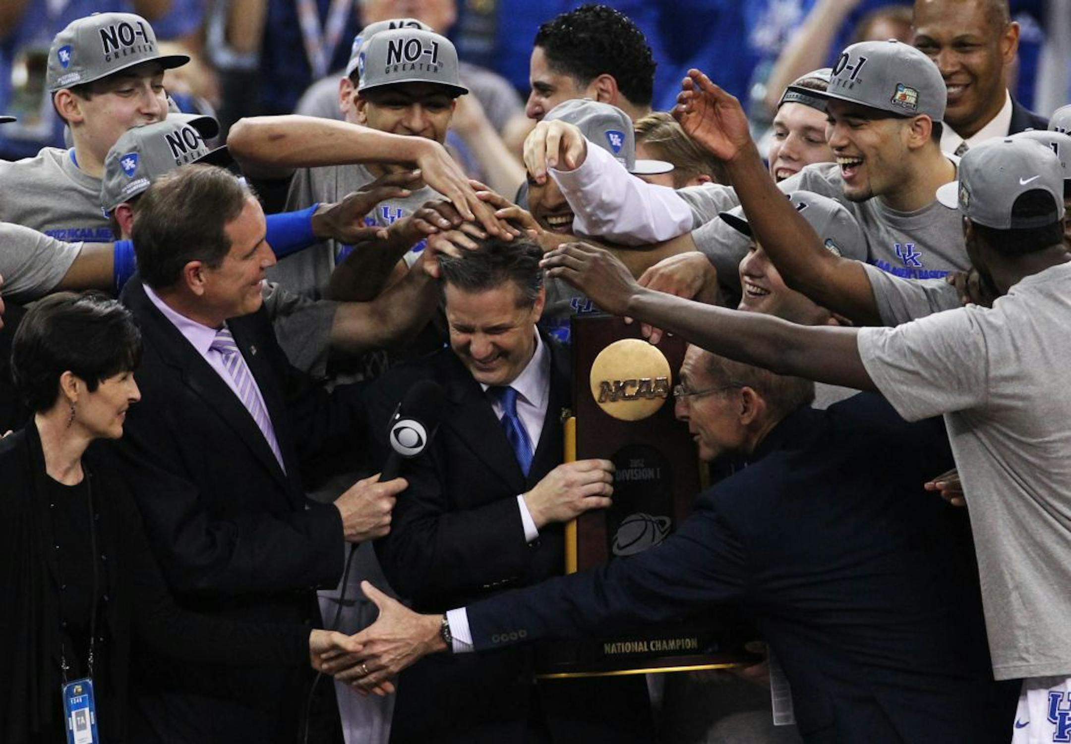 The Kentucky team mobs coach John Calipari after being awarded the championship trophy following a 67-59 win over Kansas on Monday.