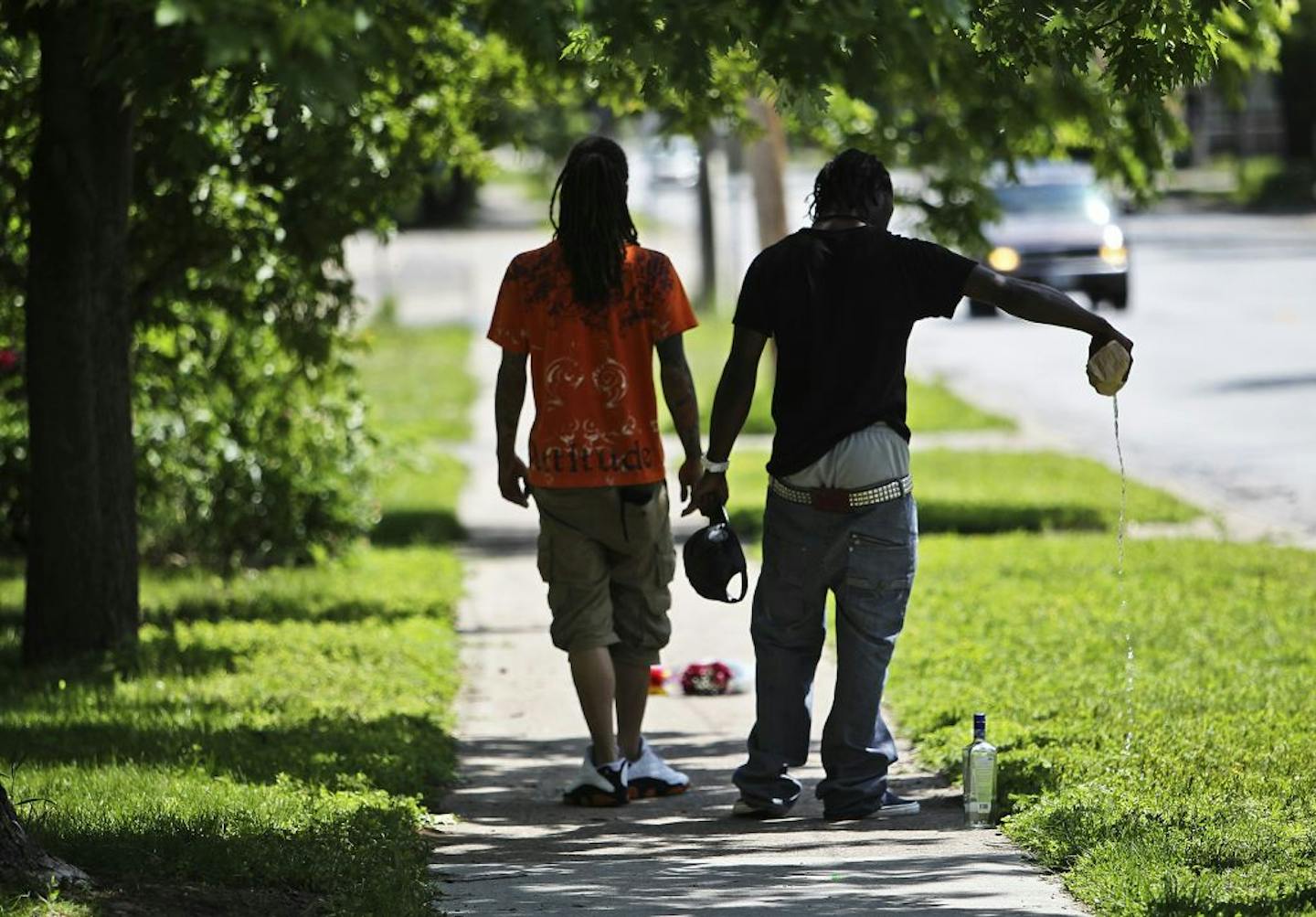 Two men walk past the shooting scene, one pouring out liquid from a bottle before taking a drink at the shooting scene near 53rd and Emerson Avenues N. A Brooklyn Center police officer shot and killed Dontay Wright, 20, a student at Brooklyn Center Academy who was about to graduate this coming Thursday, who was said to be carrying a rifle while walking down the middle of the street.