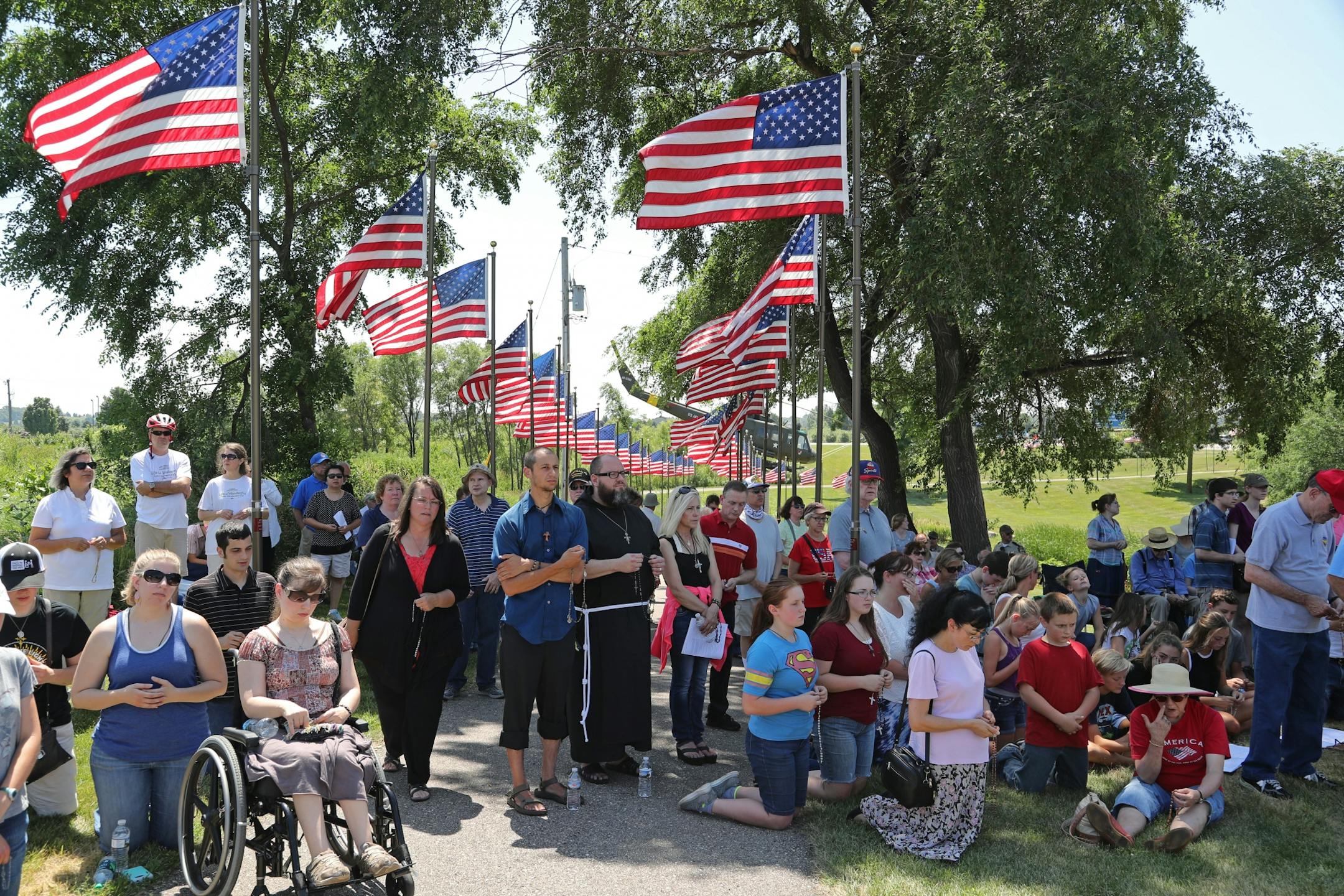 Catholic protesters gather at Veterans Memorial Park in Belle Plaine to protest inclusion of satanic symbol statue. The memorial depicting a soldier kneeling by a cross was removed Friday.