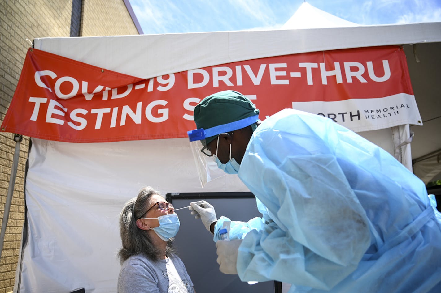 Finn Marube, a clinical scientist with North Memorial, administered a COVID-19 test to Sandra Lynn White, of Minneapolis, Wednesday afternoon behind the North Memorial Health Specialty Center. ] aaron.lavinsky@startribune.com Healthcare workers tested drive-up and walk-up patients for COVID-19 behind the North Memorial Health Specialty Center on Wednesday, July 29, 2020 in Robbinsdale, Minn.