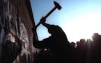 FILE - This Nov. 12, 1989 file photo shows a man hammering at the Berlin Wall, as the border barrier between East and West Germany was torn down after