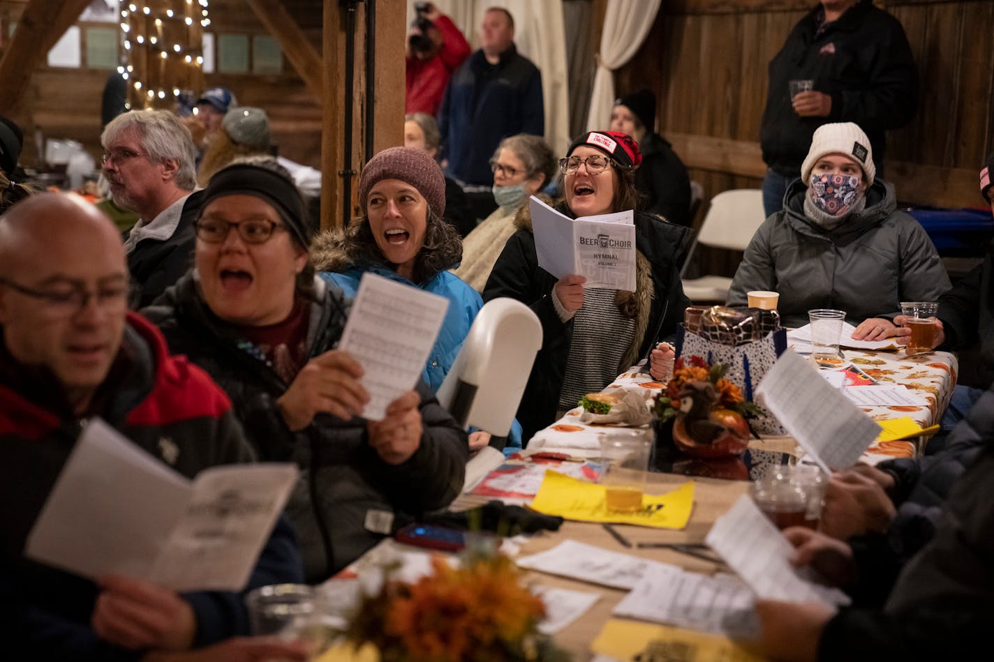 Meg Gronau, of Maplewood, (in blue coat) and Ellen Ryan of Minneapolis, (in red hat) sing along with more than 75 other people that participated in the Beer Choir Twin Cities event at the Maplewood Historical Society on Wednesday, Nov. 24, 2021.