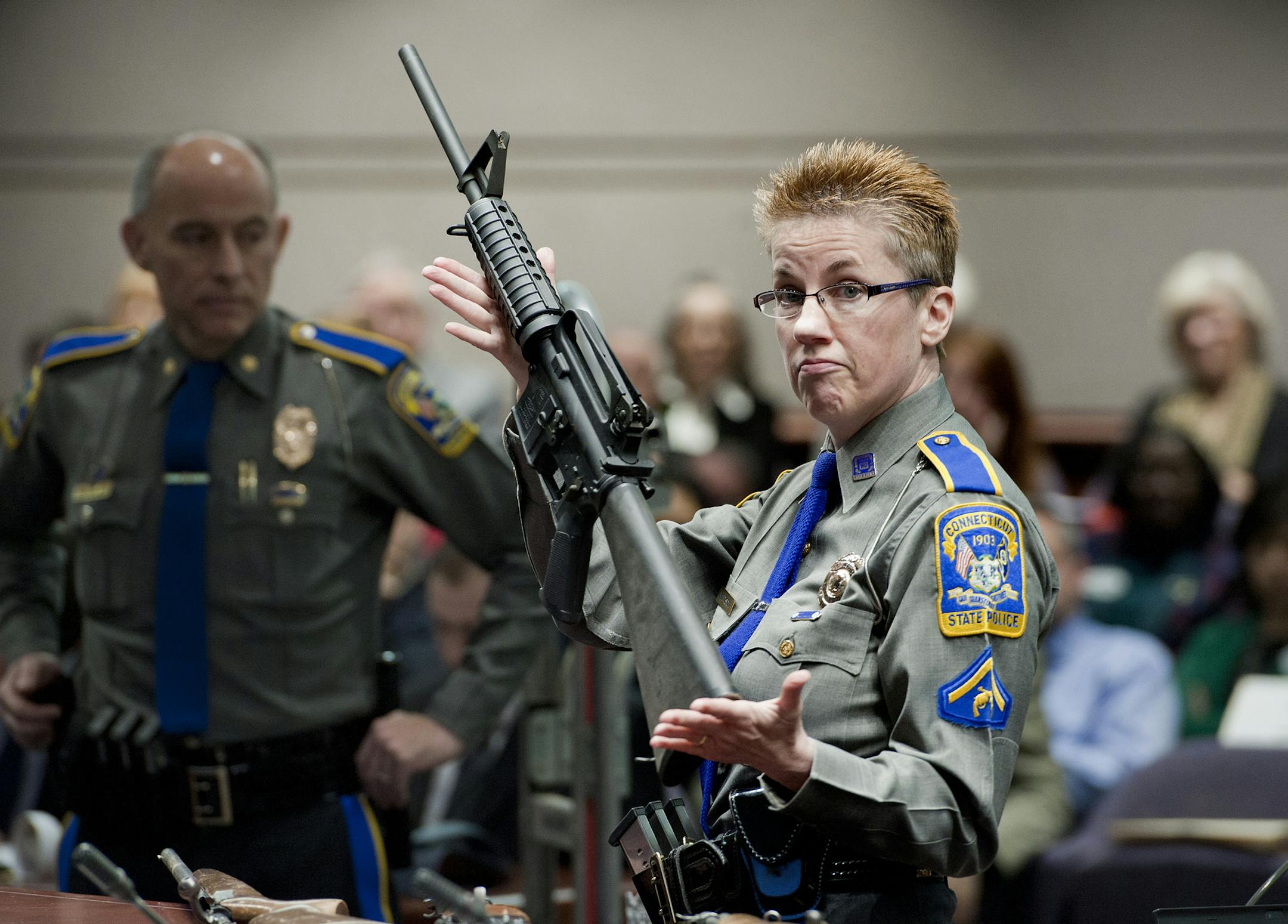 FILE - In this Jan. 28, 2013, file photo, firearms training unit Detective Barbara J. Mattson, of the Connecticut State Police, holds up a Bushmaster AR-15 rifle, the same make and model of gun used by Adam Lanza in the December 2012 Sandy Hook School shooting, during a hearing of a legislative subcommittee in Hartford, Conn. Gunmaker Remington Arms filed a request on Thursday, Aug. 1, 2019, asking the U.S. Supreme Court to hear its appeal of a Connecticut court ruling that reinstated a wrongful