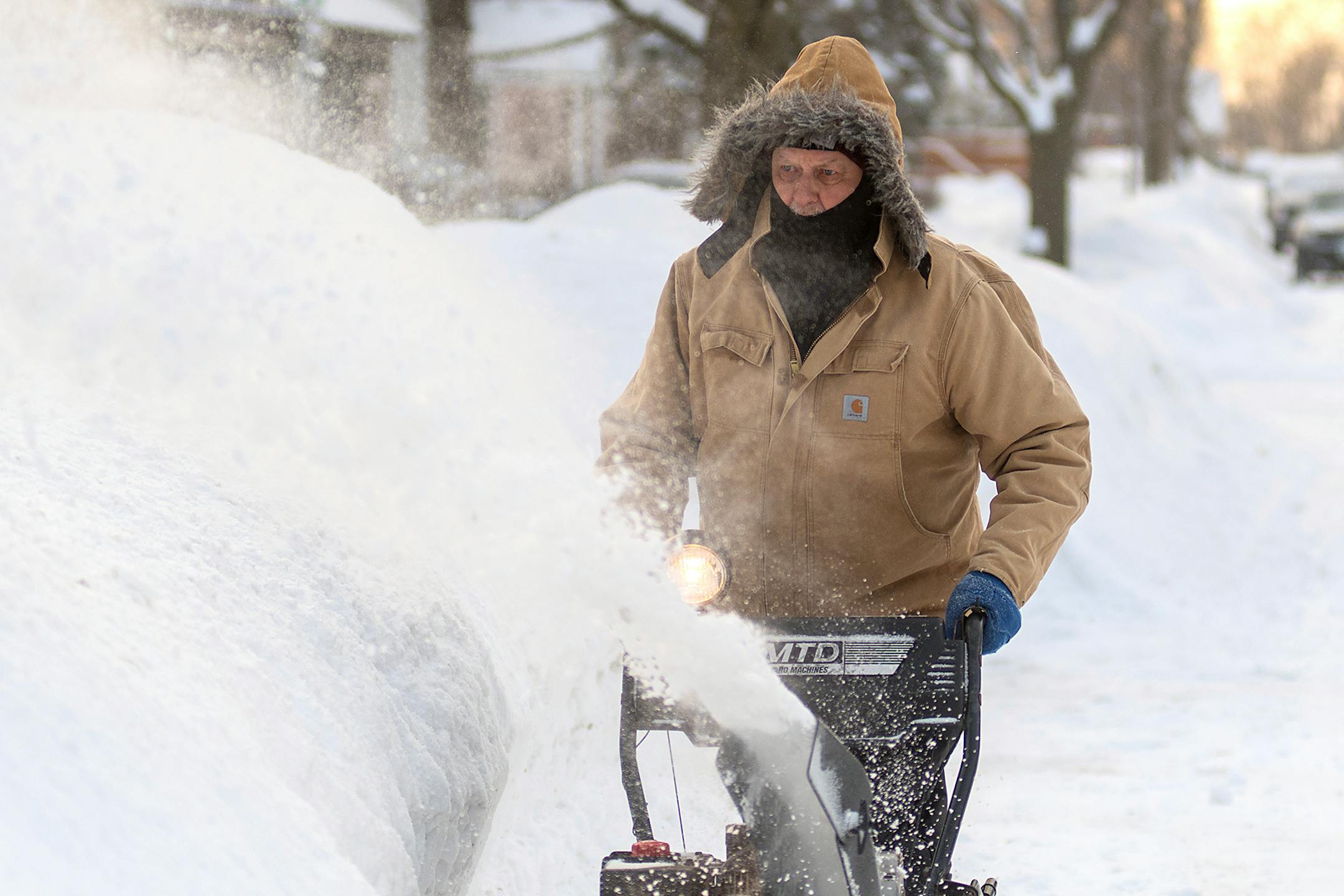 Jim Adam blows snow in front of his house on West Lewis Street in Mankato, Minn.