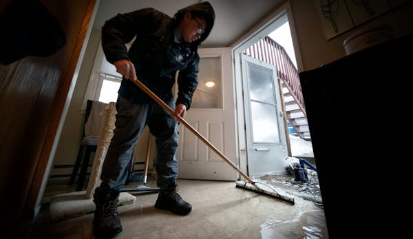 Josue Huerta of Service Restoration squeegeed a few inches of water from a flooded basement caused by melting snow and rain, in the west metro area.