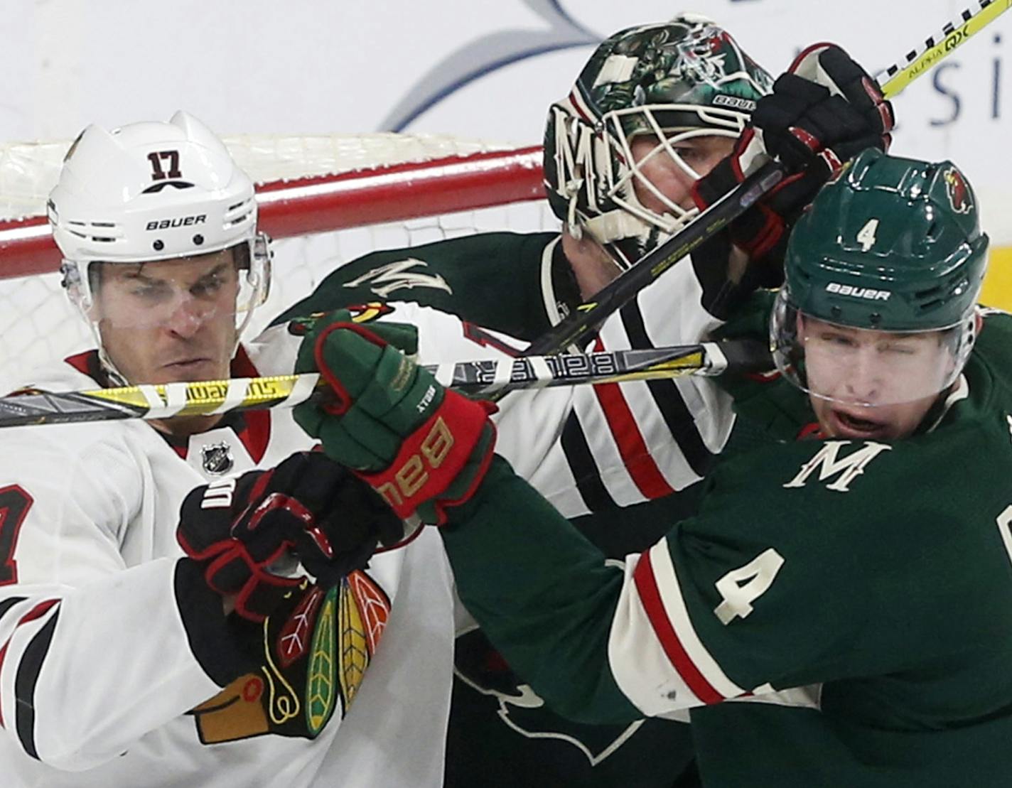 Minnesota Wild goalie Devan Dubnyk, center, tries to get a better view as Mike Reilly, right, ties up Chicago Blackhawks' Lance Bouma in front of the net in the second period of an NHL hockey game, Saturday, Feb. 10, 2018, in St. Paul, Minn. (AP Photo/Jim Mone)