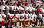 Members of the San Francisco 49ers kneel during the national anthem as others stand during the first half of an NFL football game against the Arizona 