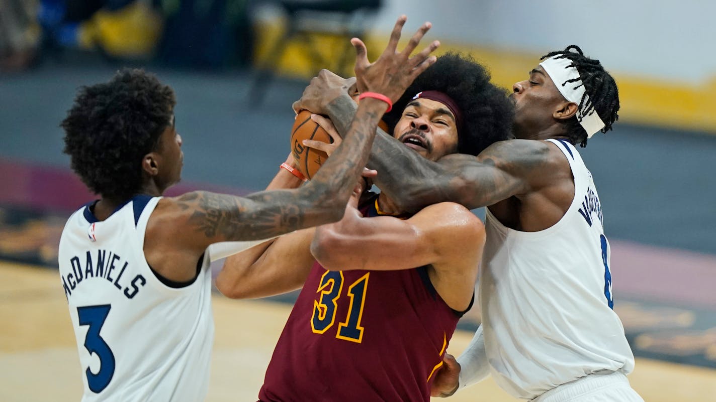 Minnesota Timberwolves' Jarred Vanderbilt, right, fouls Cleveland Cavaliers' Jarrett Allen (31) as Timberwolves' Jaden McDaniels, left, defends in the first half of an NBA basketball game, Monday, Feb. 1, 2021, in Cleveland. (AP Photo/Tony Dejak)