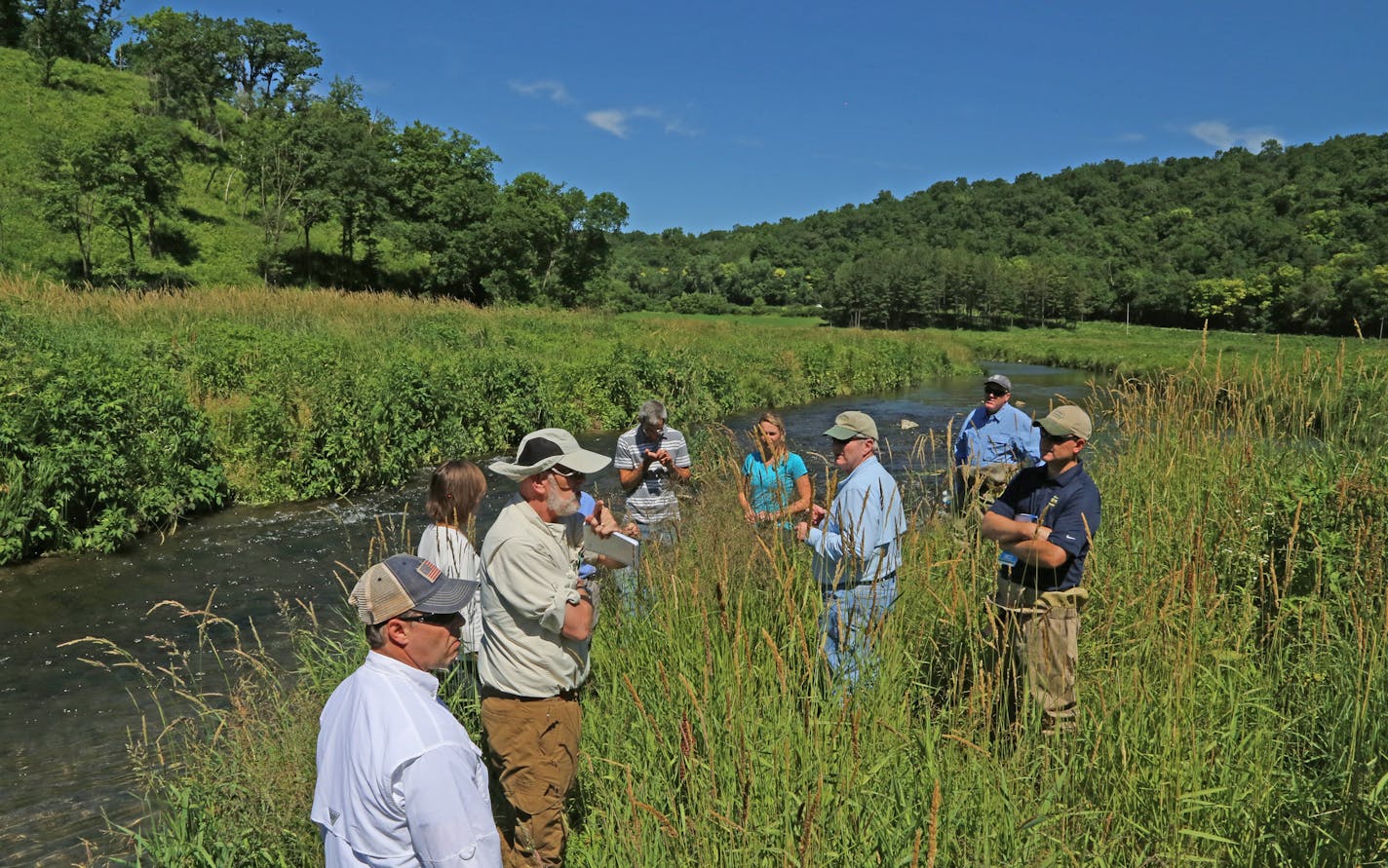 Infectious disease specialist Dr. Michael Osterholm of the University of Minnesota, center, explains his trout stream rehabilitation methods at Prairie Song Farm, his northeastern Iowa retreat. Osterholm has spent many years of work and experimentation to reclaim trout streams on his property.