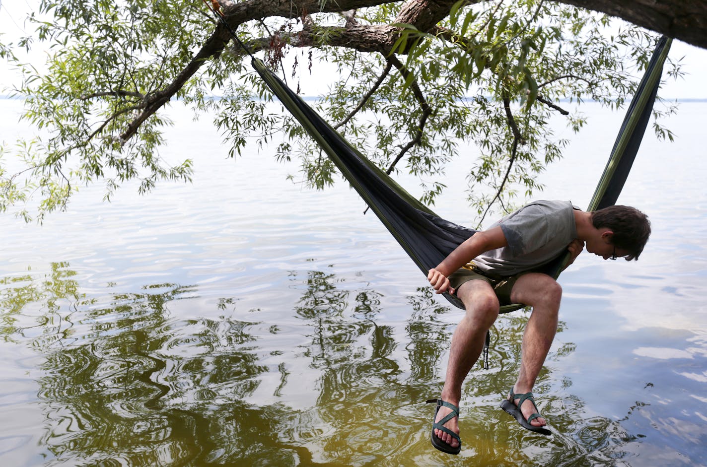 Kristofer Munkel of Madison hangs from his hammock over Lake Mendota in search of his car key he accidentally dropped into the water at Tenney Park in Madison, Wis.