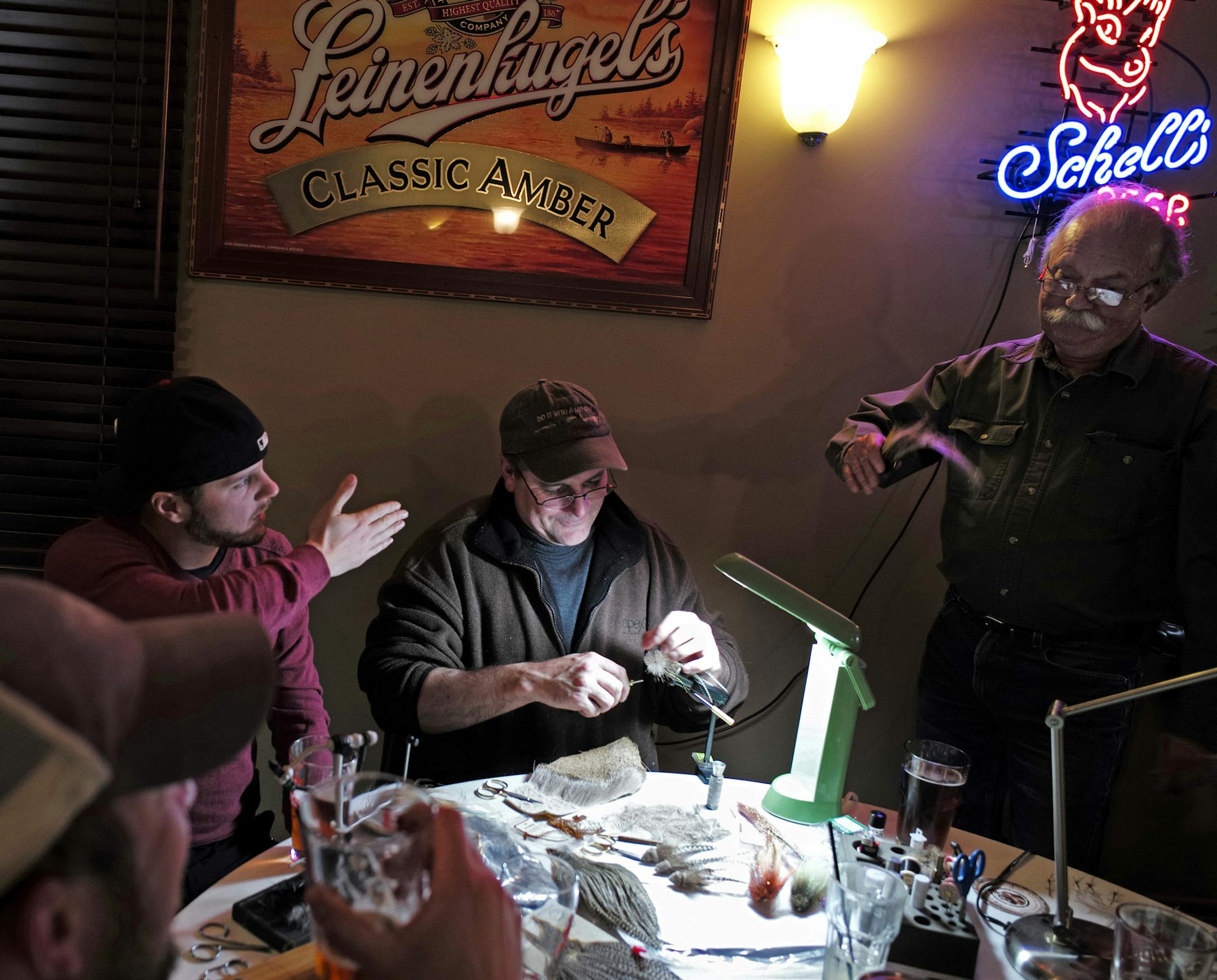 At Schroeder's Bar & Grill in St. Paul, Adam Pavek(red), Tony Stifter, and, Bob Anderson, far right, discuss how this particular bass fly by Stifter would move through the water to mimic a minnow.]richard tsong-taatarii/rtsong-taatarii@startribune.com ORG XMIT: MIN1312262205554183