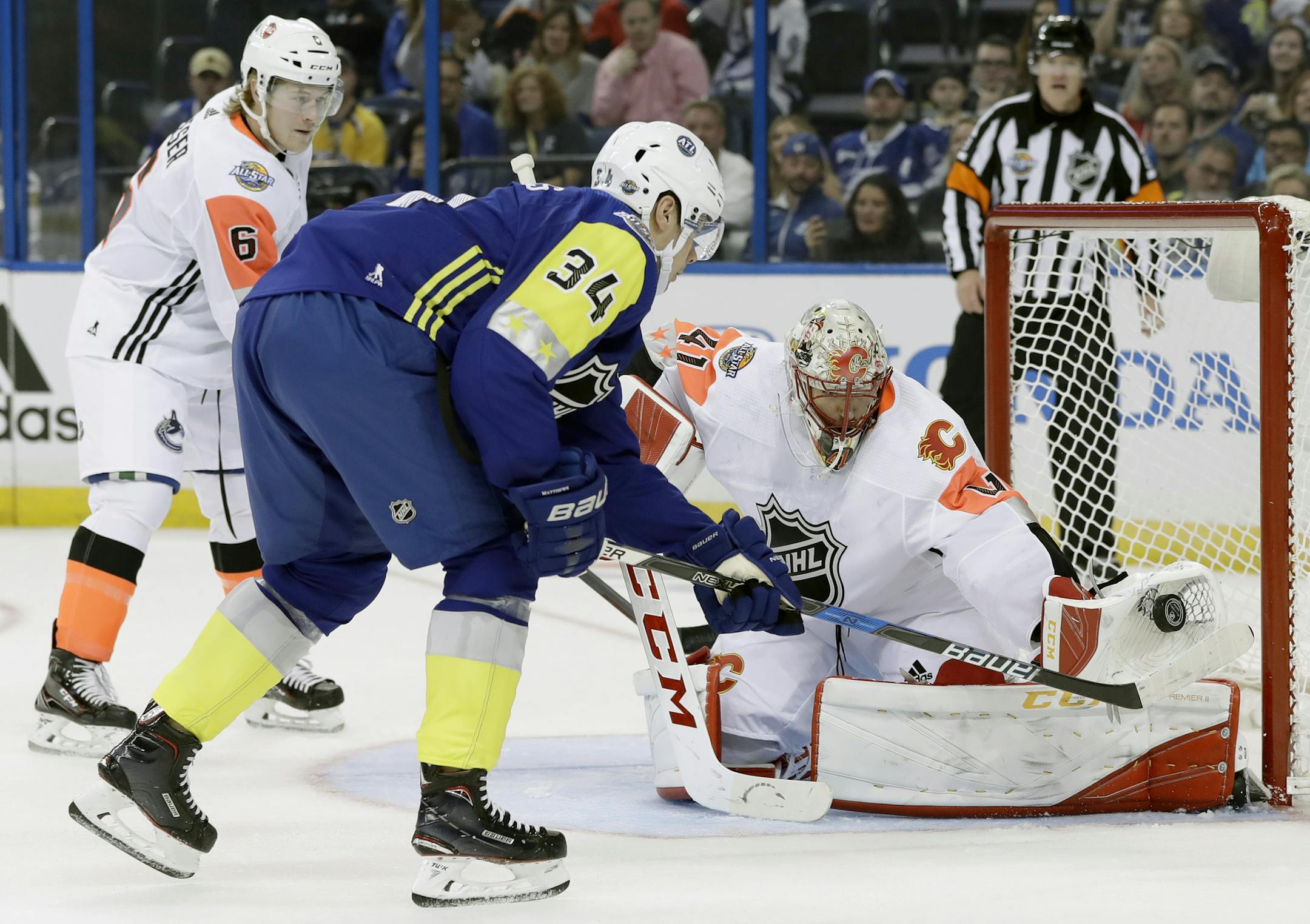 Pacific Division goalie Mike Smith of the Calgary Flames made a glove save on a shot by the Atlantic Division's Auston Matthews (34) of the Toronto Maple Leafs, as Brock Boeser (6), of the Vancouver Canucks, watched during the NHL All-Star Game on Sunday in Tampa, Fla., last year.