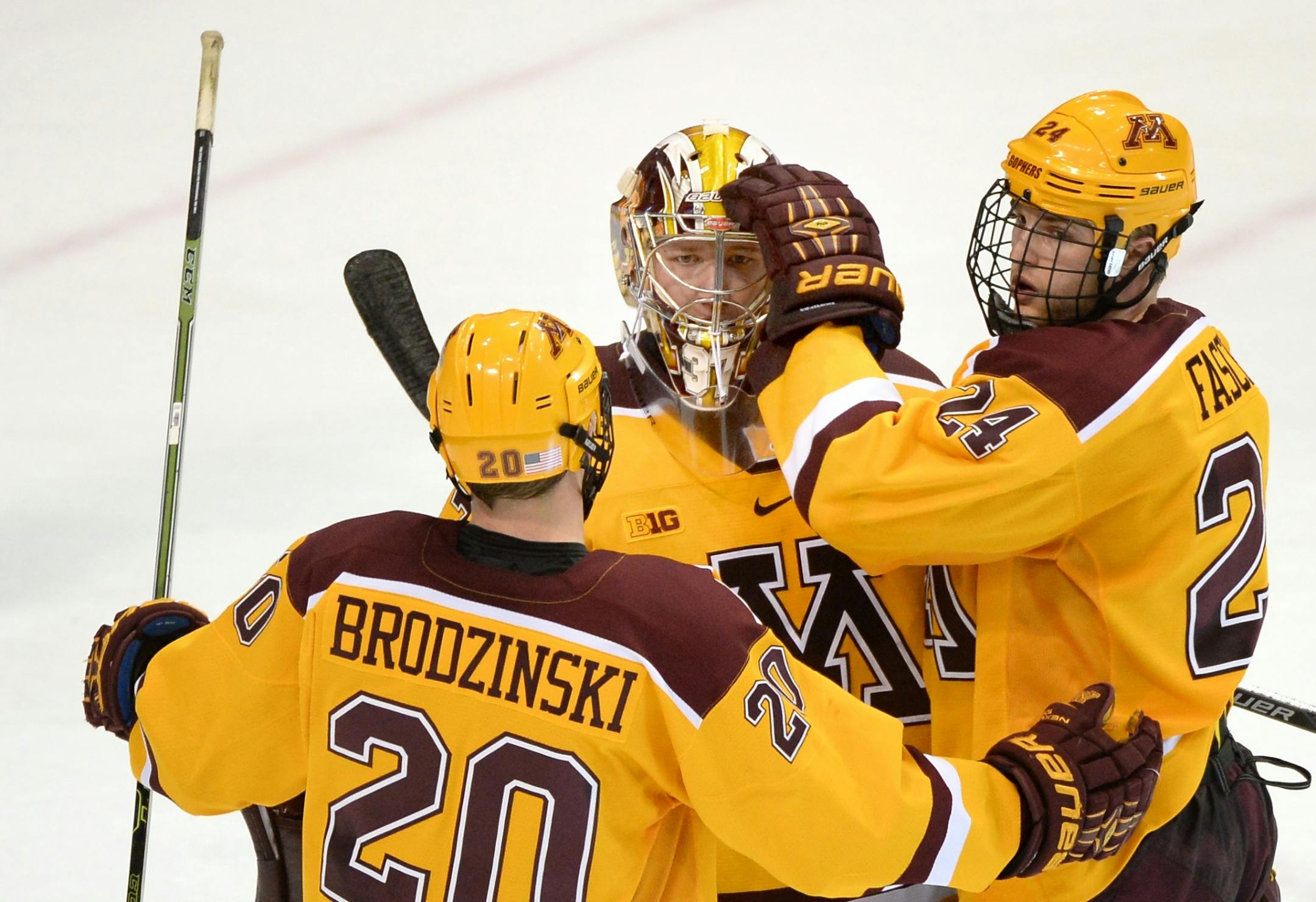 Minnesota Golden Gophers defenseman Michael Brodzinski (20) and right wing Hudson Fasching (24) comforted starting goalie Eric Schierhorn (37) after their team's 5-3 loss to the Michigan Wolverines in the Big 10 championship game Saturday.