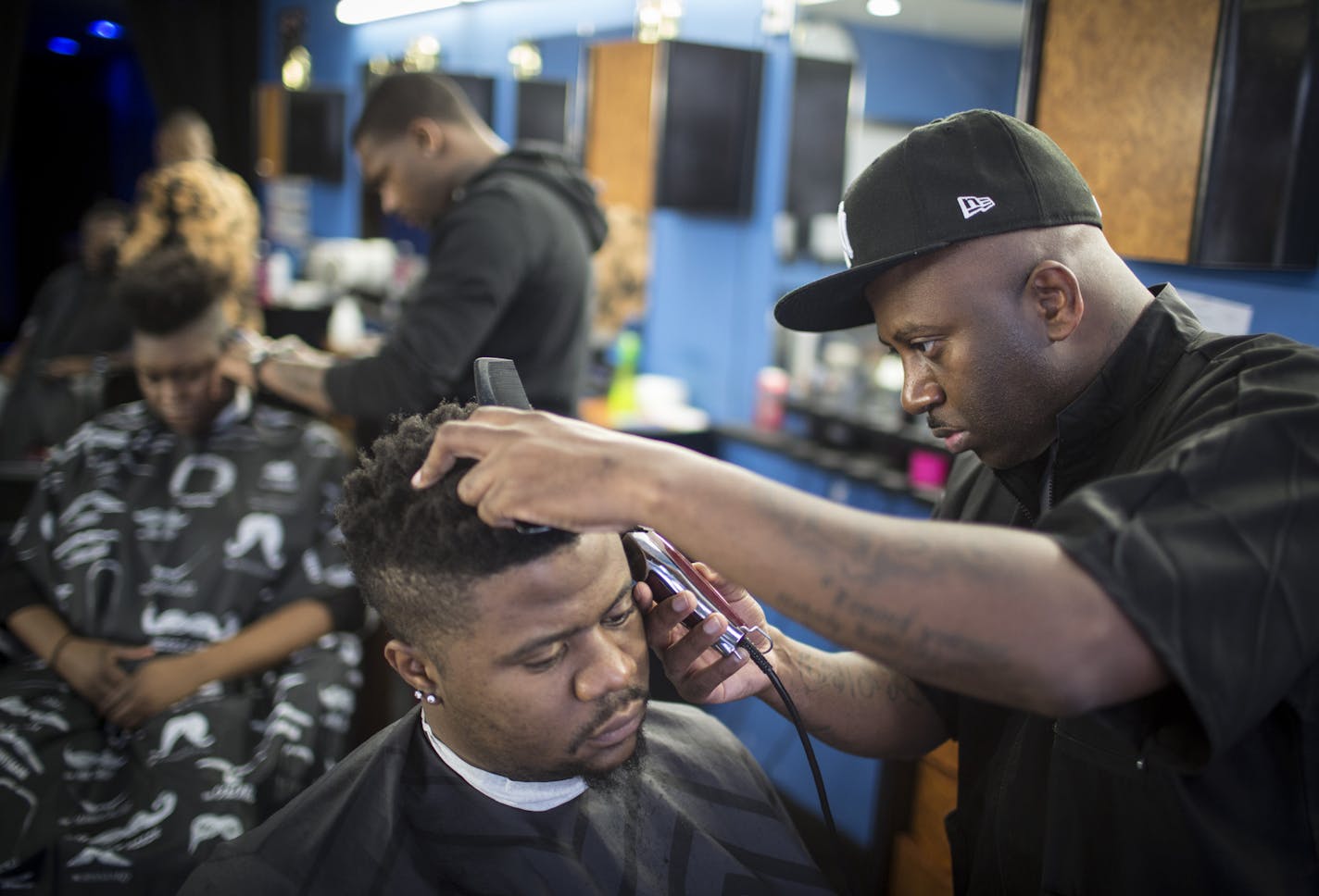 The Heights Barber Lounge owner Juan Collier cut customer Senghor Shinwen's hair. Many of Collier's neighbors in Columbia Heights are automotive businesses. The city would like to attract a wider mix.