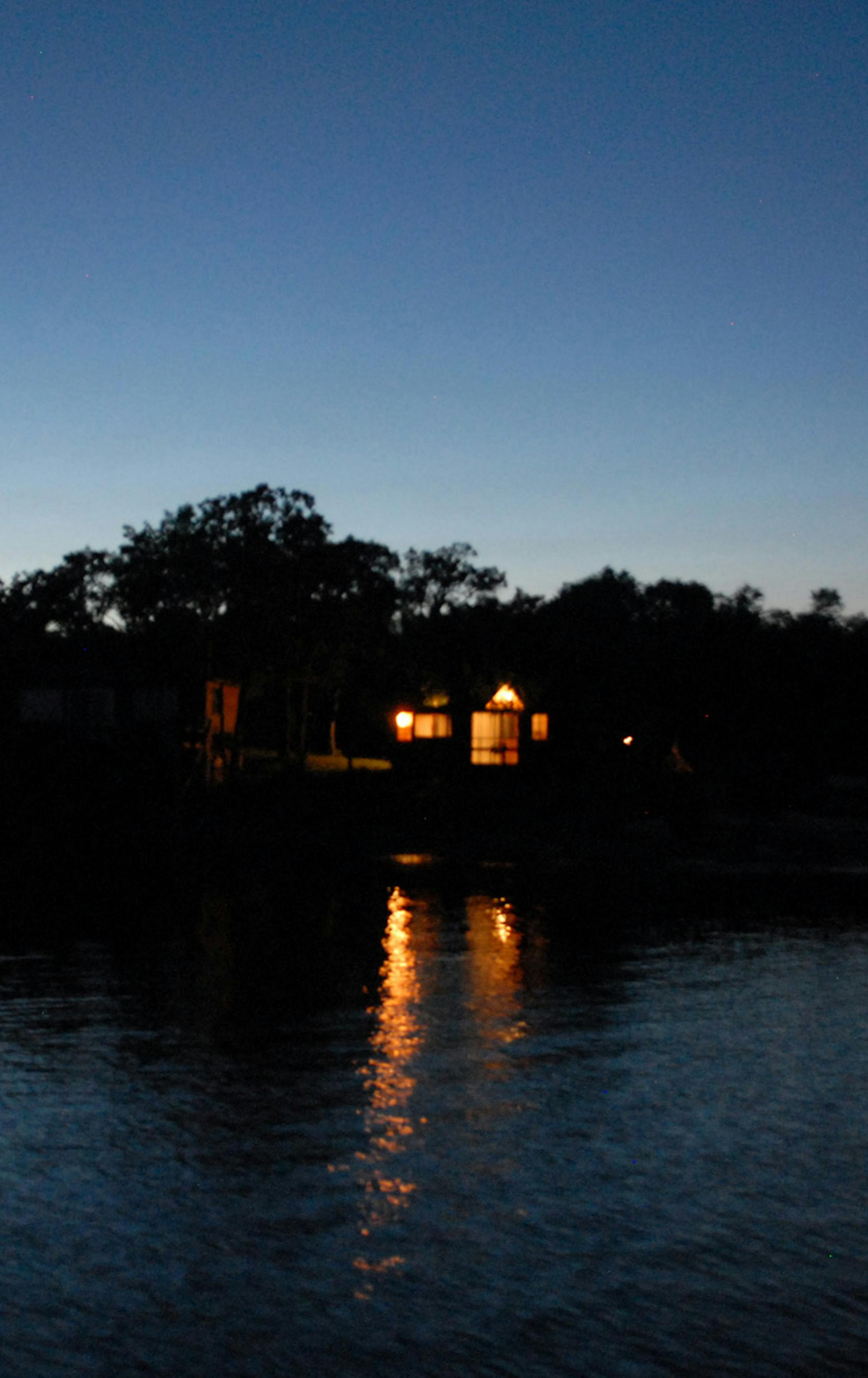 Evening lights on in an island cabin provide a warm return to Lake of the Woods muskie anglers after a long day on the water during which hundreds upon hundreds of casts might be made ‚Äî most for naught.
