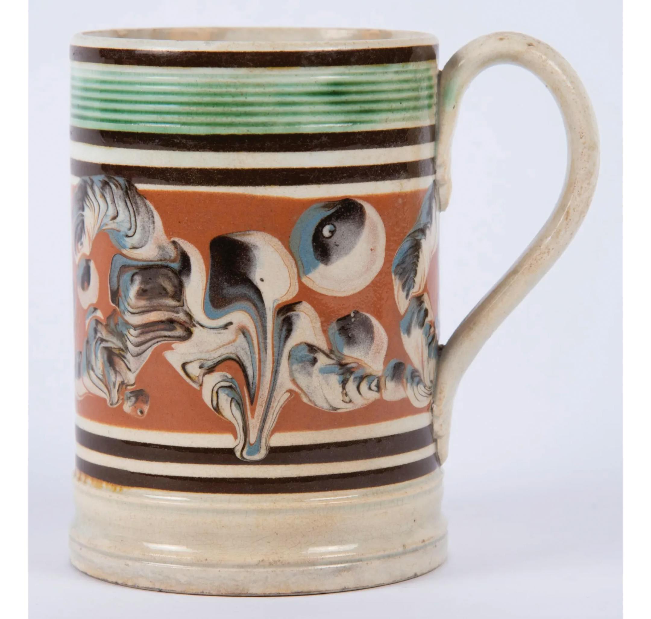 Antique mocha ware, made in England to export to the United States and Canada in the 18th and 19th centuries, caught collectors' attention in the mid-20th century. Like many mocha pieces, this colorful mug is decorated with several patterns.