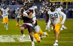 Minnesota running back Ky Thomas (8) runs away from West Virginia safety Alonzo Addae and safety Sean Mahone (29) during the first half of the Guarant