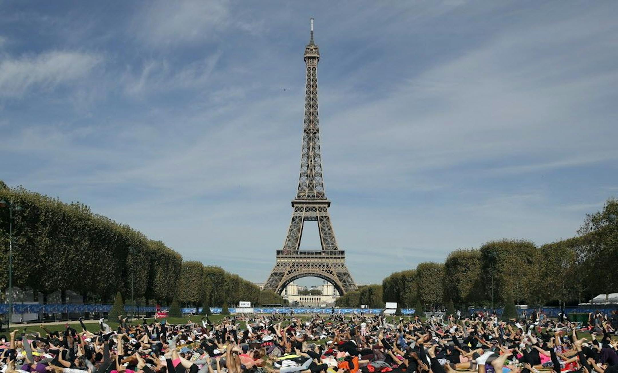 FILE - In this Saturday, Sept. 8, 2018 file photo, participants perform yoga in front of the Eiffel Tower as part of the sport event "La Parisienne", in Paris. The Eiffel Tower announces it will be closed on Saturday, Dec. 8 due to the protests called in the French capital by the yellow vest movement. Tickets bought online will be refunded, the company operating the Paris monument said on Twitter.