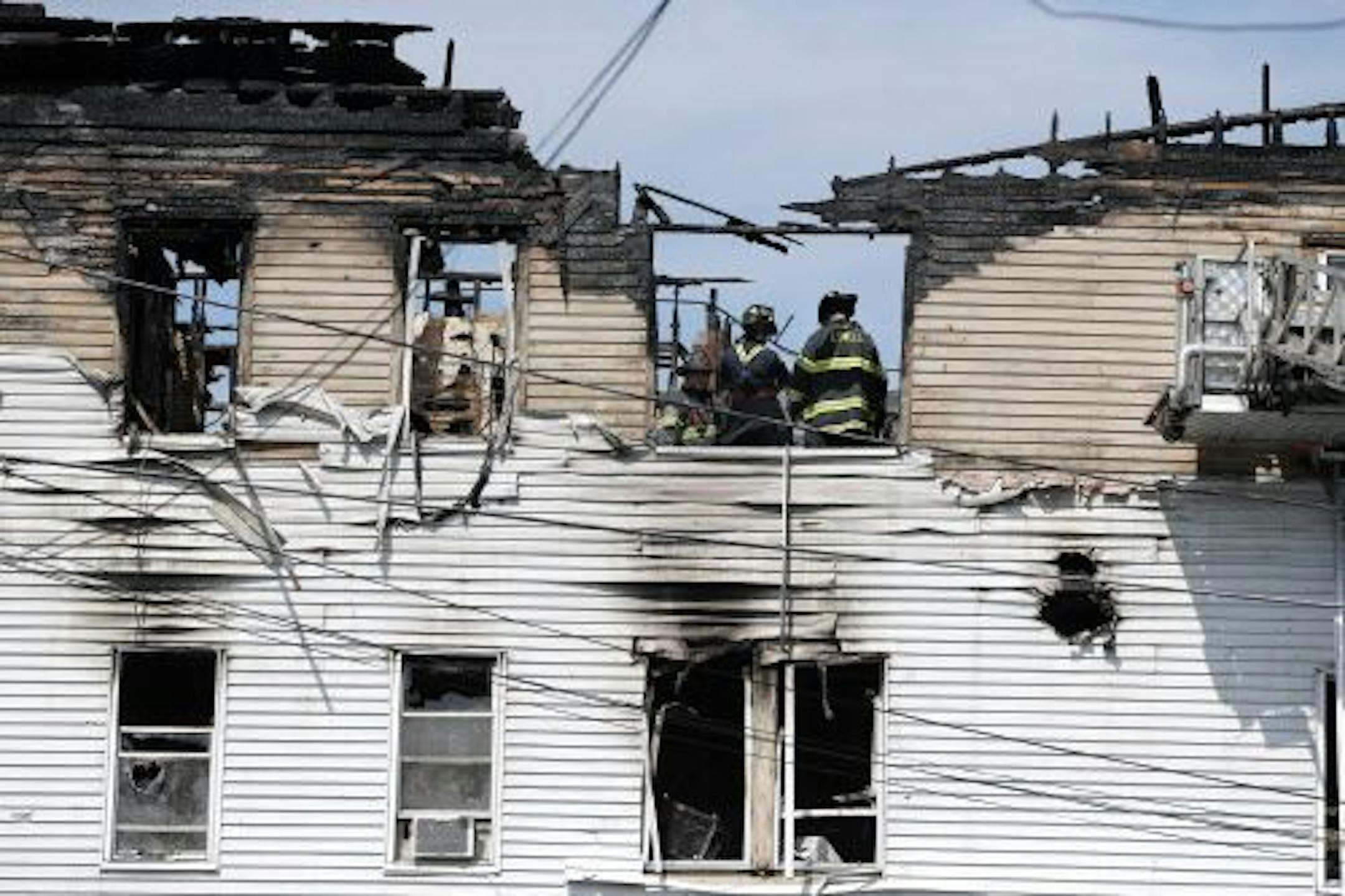 Firefighters work on the top floor inside a burned three-story apartment and business building in Lowell, Mass., Thursday, July 10, 2014, where officials said seven people died.
