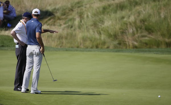 Dustin Johnson, right, talks to a rules official on the fifth green during the final round of the U.S. Open golf championship at Oakmont Country Club 