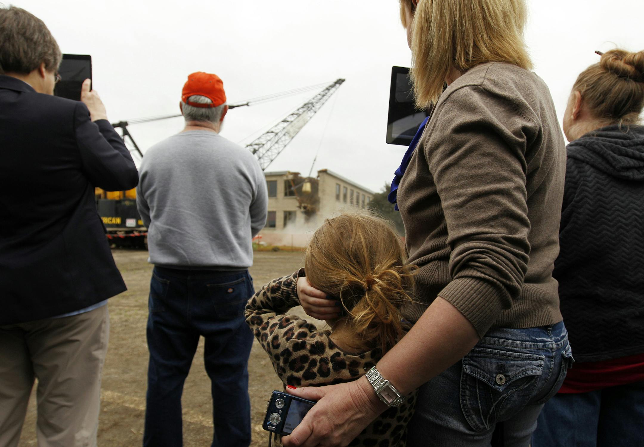 Shoreview resident Shelly Blair, second from right, takes video on her iPad as her granddaughter Alyson Grinde, 4, covers her ears during a ceremony celebrating the continued demolition of the former Twin Cities Army Ammunition Plant (TCAAP) in Arden Hills, Friday, June 7, 2013. (Genevieve Ross/Special to the Star Tribune) ORG XMIT: 02TCAAP060813