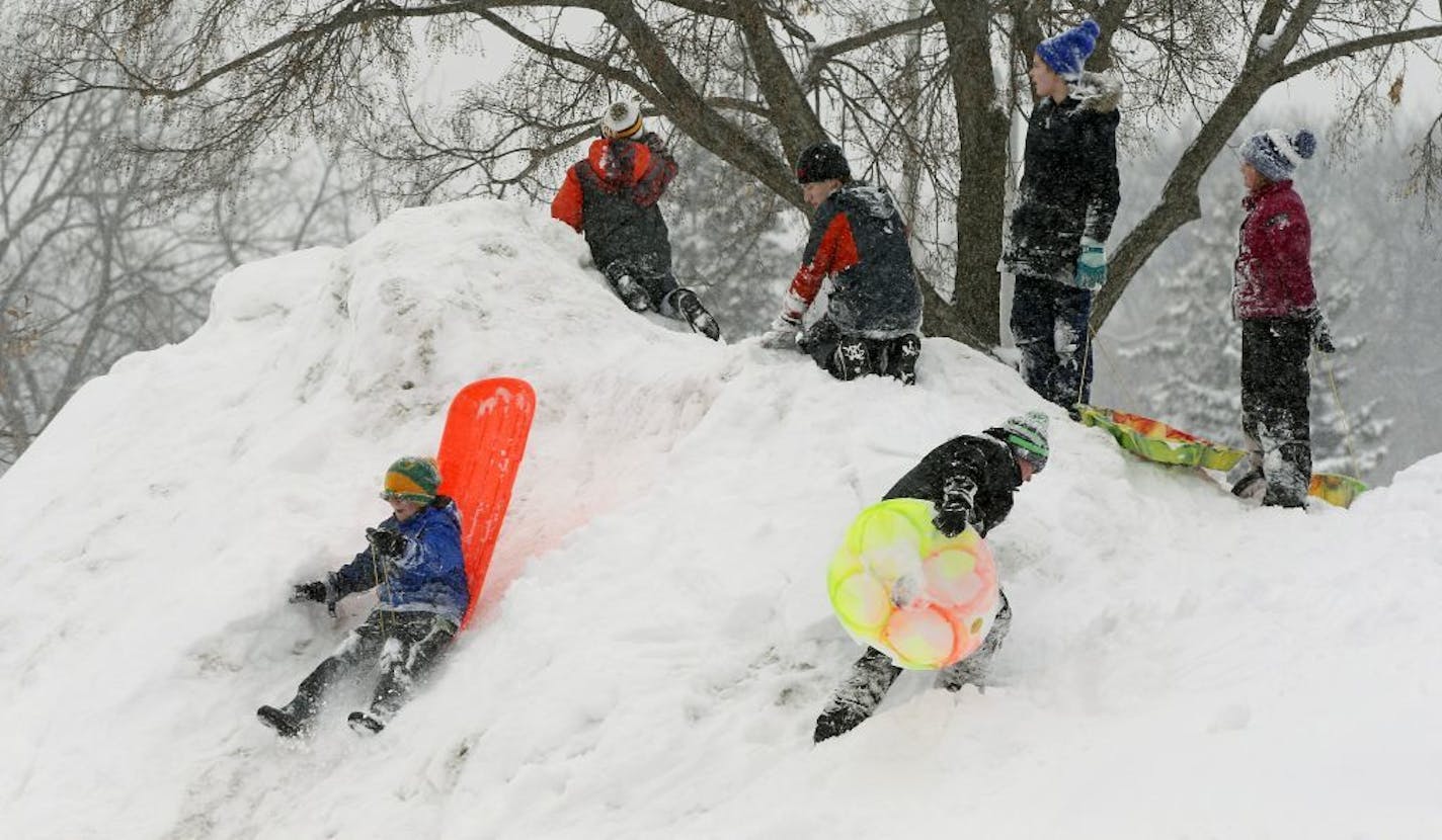 Children enjoy a mini-mountain of snow piled up from a parking lot at a park in Minneapolis where schools were closed as a snowstorm dumped seven inches, according to the National Weather Service, Wednesday, Feb. 20, 2019, setting a new snowfall record for the month of February.