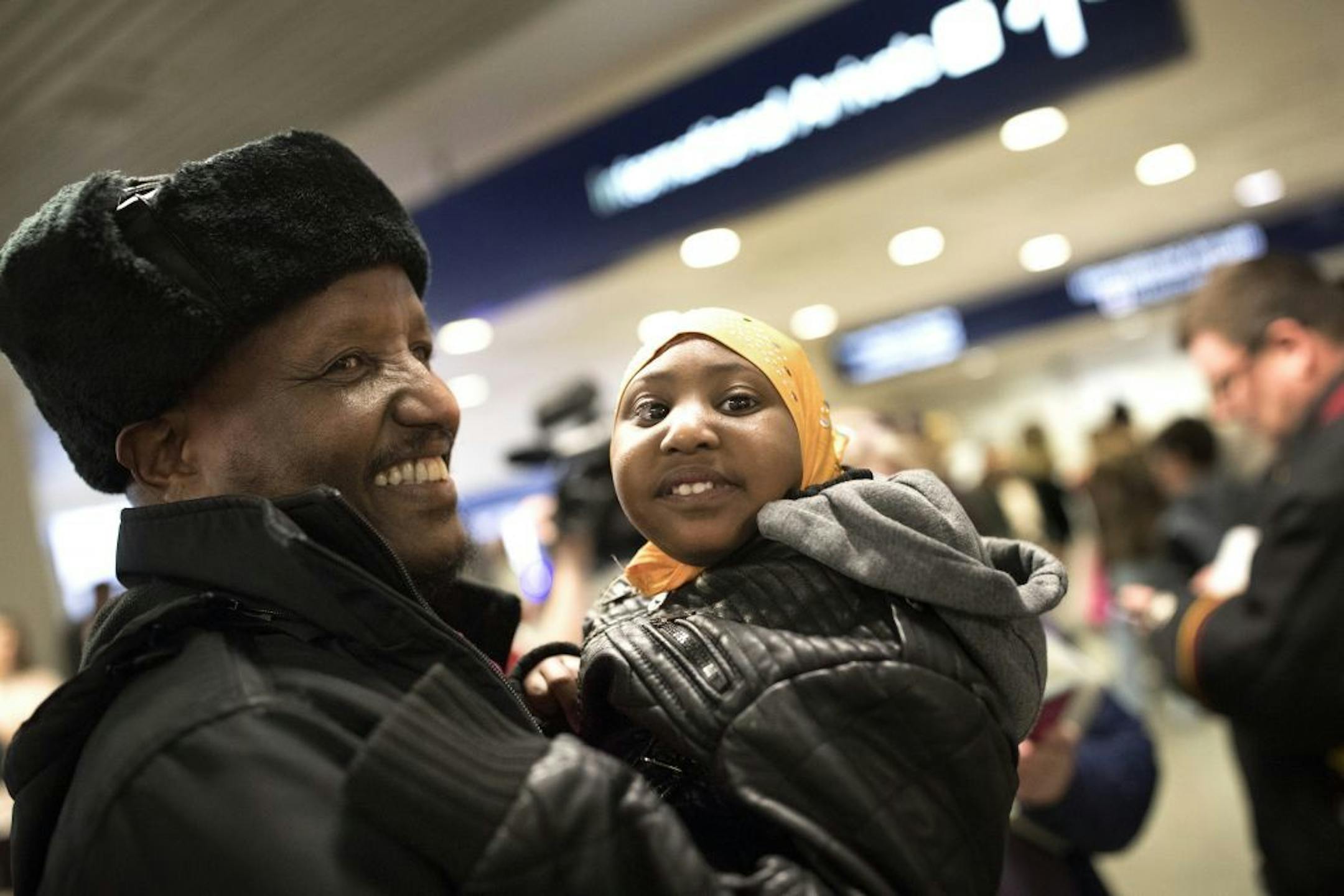 Mohamed lye holds his 4-year-old daughter Nimo as he was reunited with his wife Saido Ahmed Abdille and their other daughter Nafiso, 2, at Minneapolis-St. Paul International Airport near Bloomington, Minn., after arriving from Amsterdam on Sunday, Feb. 5, 2017.