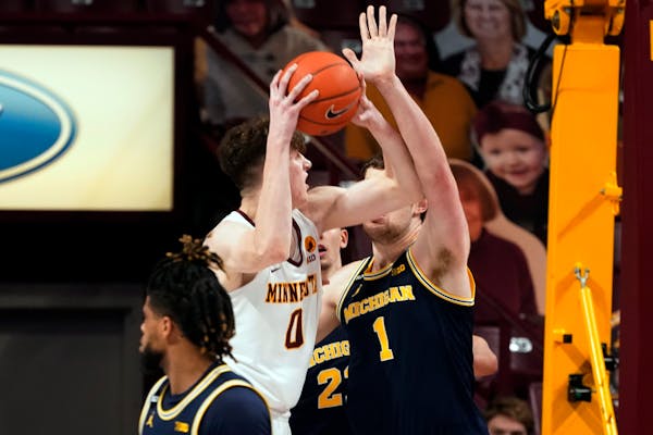 Minnesota's Liam Robbins (0) eyes the basket as Michigan's Hunter Dickinson (1) defends in the second half of an NCAA college basketball game, Saturda